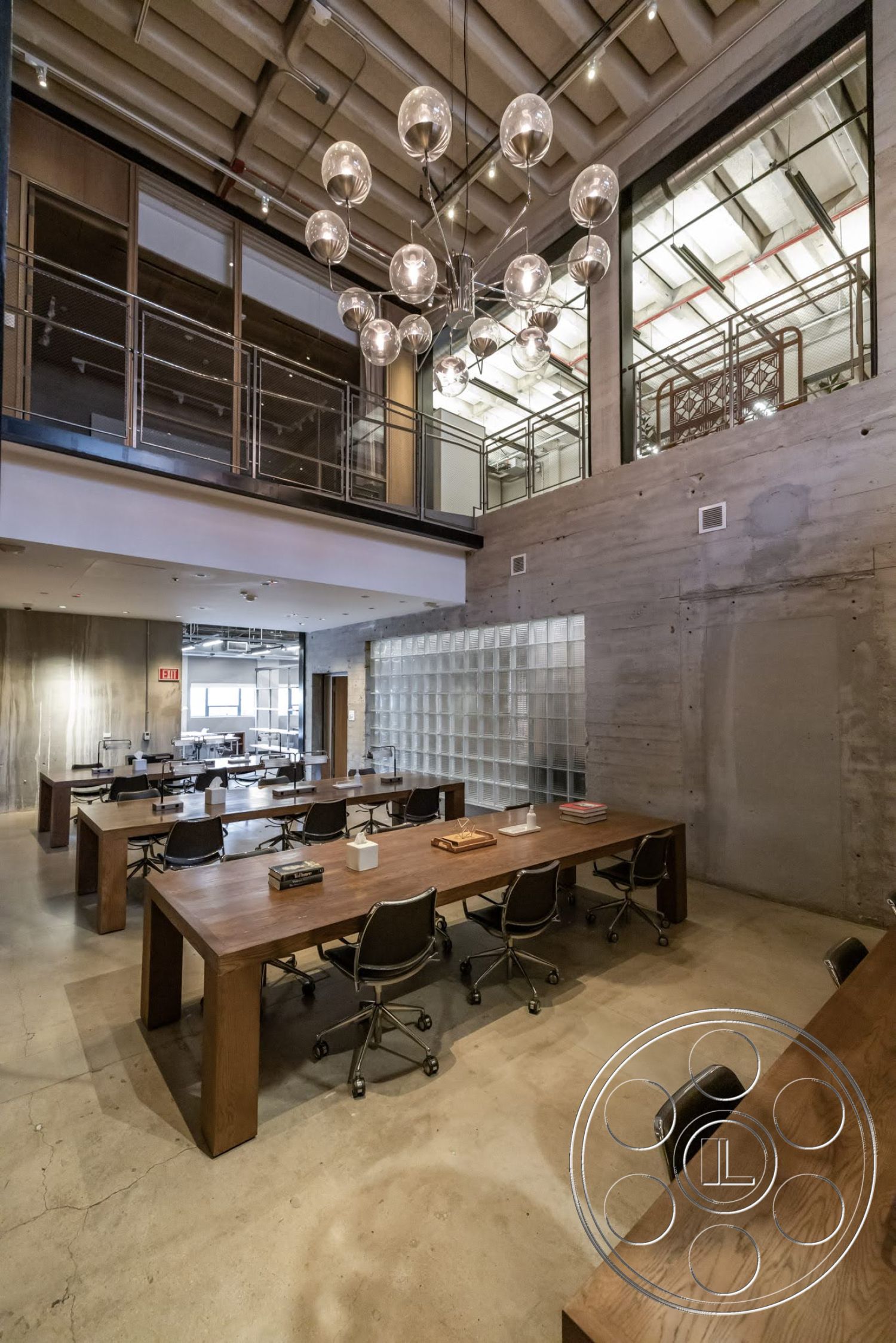 Sunset Campus - large windows, minimalist design, open floor plan, polished concrete flooring, exposed concrete walls, collaborative workspace, steel railing, urban office setting, mesh office chairs, high ceiling with exposed beams, wood conference tables, modern industrial lighting fixture, glass block wall partition
