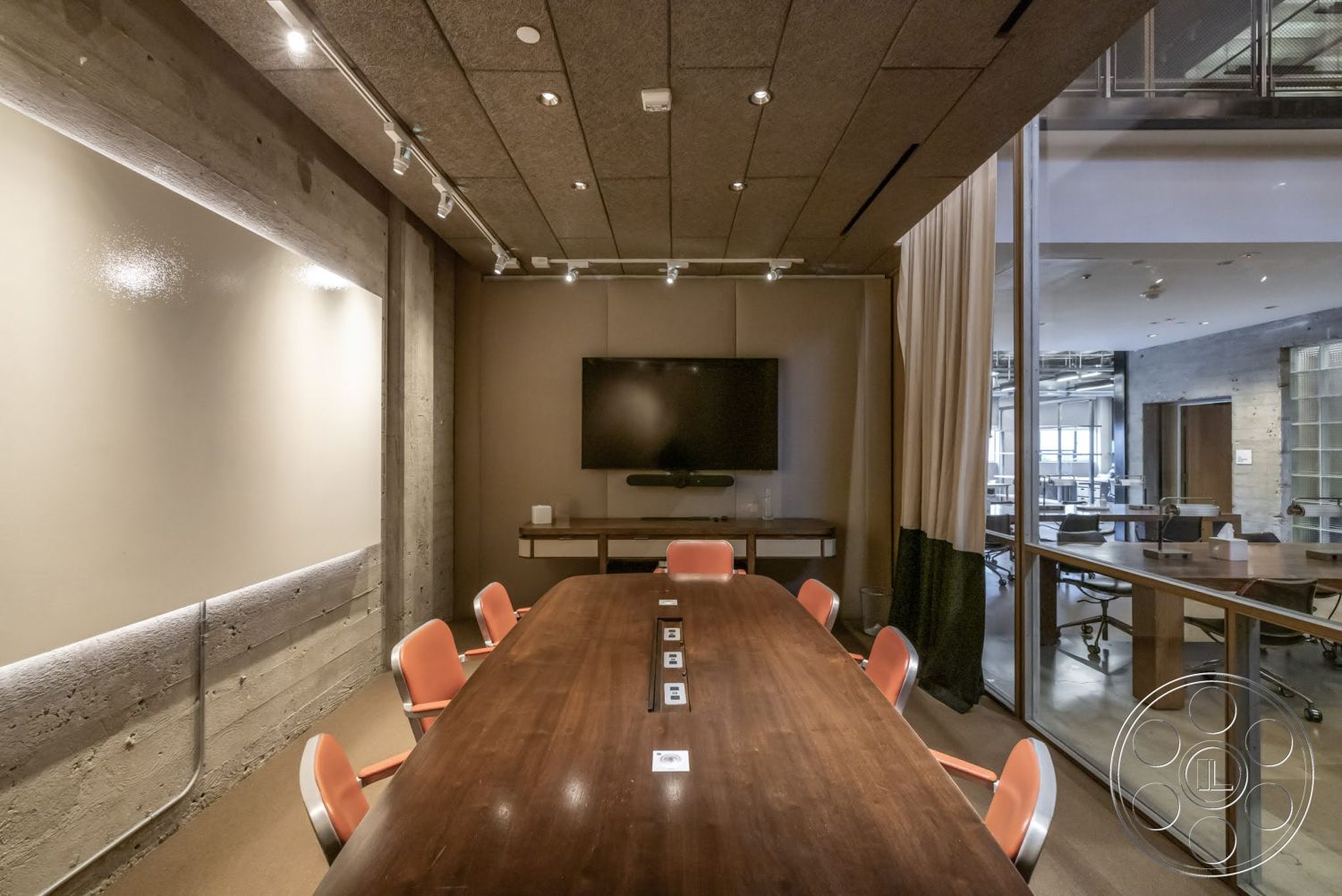 Sunset Campus - polished concrete flooring, exposed concrete walls, soft lighting fixtures, glass partition walls, modern office environment, textured acoustic ceiling panels, wood conference table, orange padded chairs, built-in media display