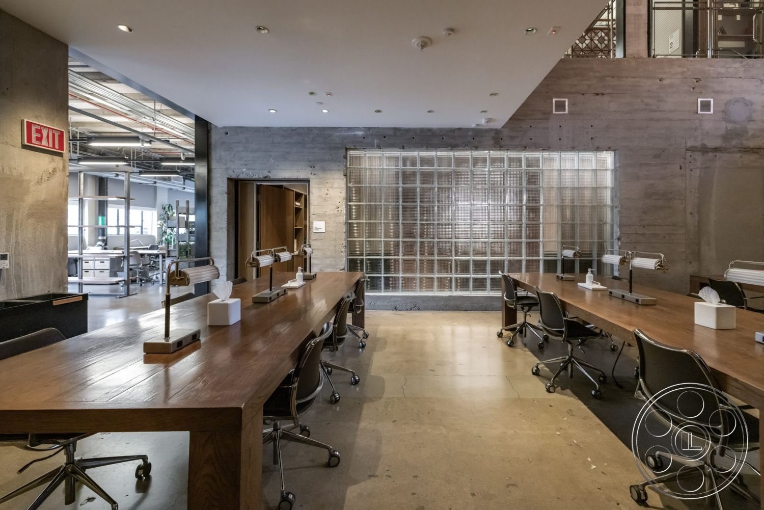 Sunset Campus - concrete walls, exposed concrete ceiling, recessed ceiling lights, open office layout, glass block wall, industrial-style interior, metal office chairs, hardwood conference table, steel architectural details
