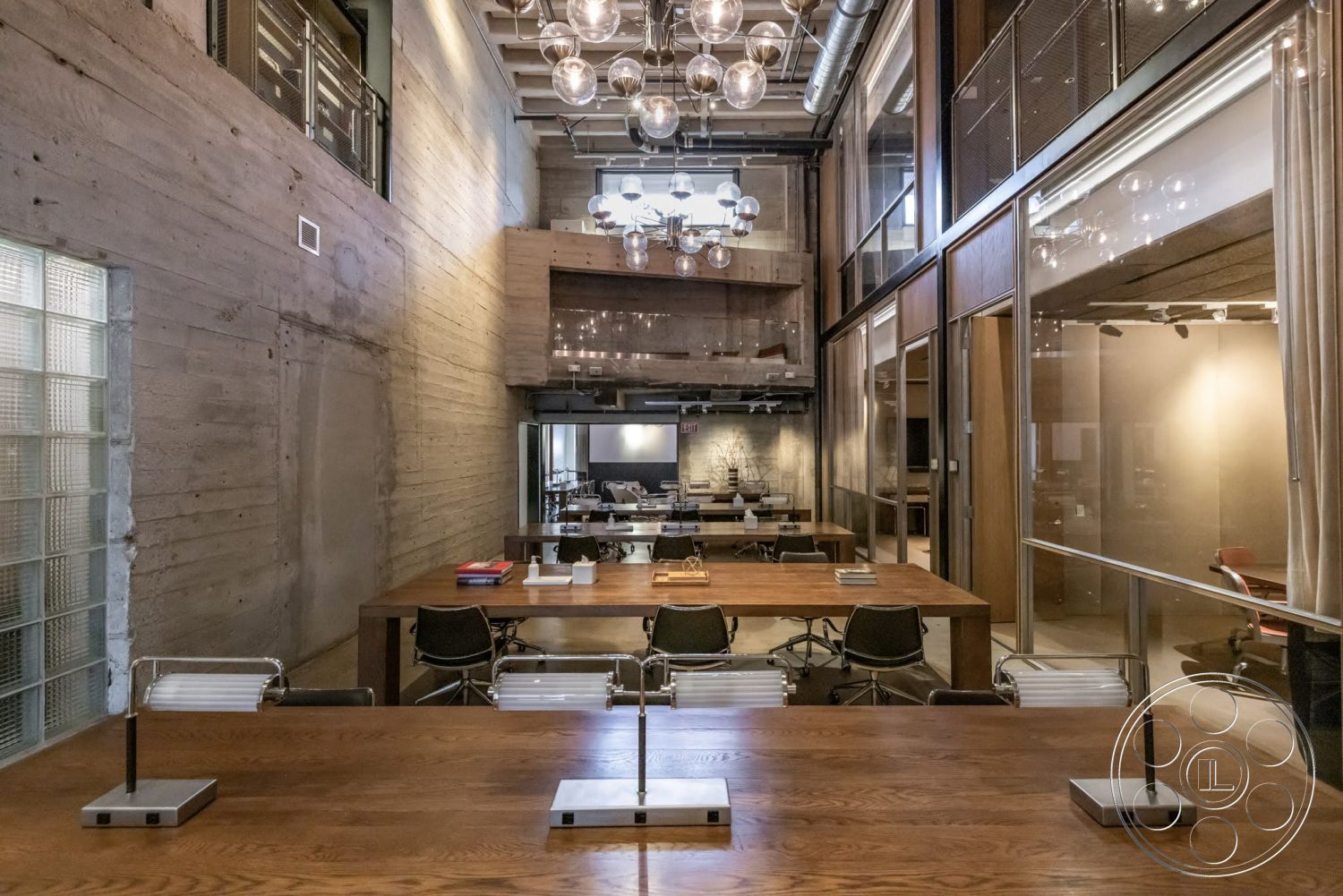Sunset Campus - minimalist aesthetic, concrete flooring, exposed concrete walls, wooden ceiling beams, pendant lighting fixtures, glass partition walls, modern workspace design, metal office chairs, industrial style ceiling, hardwood conference table, open floor plan office, large windows with glass blocks