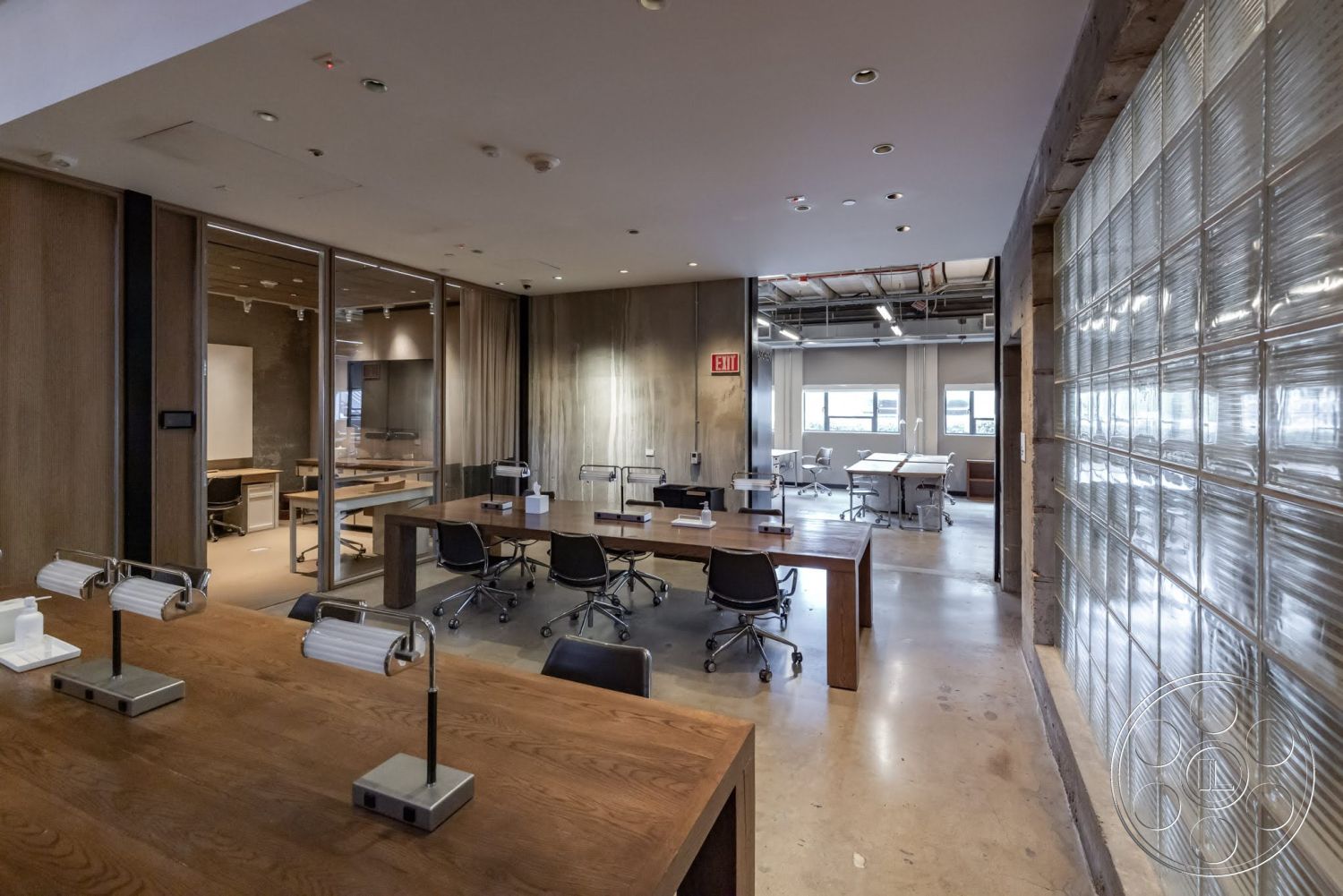 Sunset Campus - polished concrete flooring, exposed ceiling structure, open office layout, glass block wall, wood panel wall, curtained window treatments, metal desk lamps, rectangular meeting tables, modern conference room furniture, roll-top office chairs, brightly lit office space