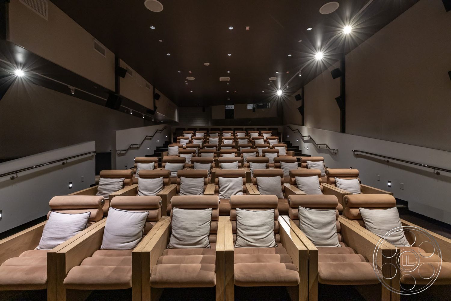 Sunset Campus - carpet flooring, dark wood paneling, recessed ceiling lighting, flush mount ceiling lights, acoustic wall panels, soft fabric throw pillows, theater room, upholstered seating with wood accents, tiered seating arrangement
