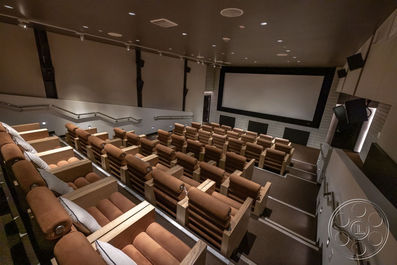 Sunset Campus - carpet flooring, raised seating area, large projection screen, ambient recessed lighting, metal railing details, wood paneling accents, sound system speakers, acoustic wall treatments, interior home theater, dark painted ceiling, reclining leather theater seats, theater room