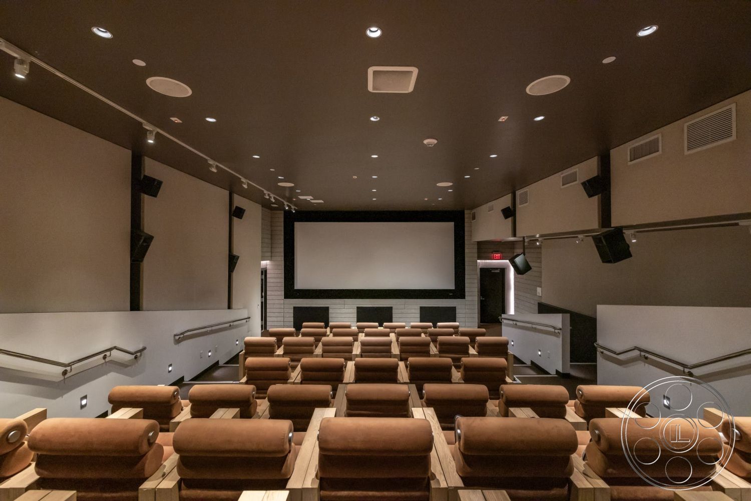 Sunset Campus - acoustic panels, projector screen wall, theater room, carpeted auditorium flooring, dark ceiling with recessed lighting, fabric theater seating with armrests, wooden seat bases, soundproof wall treatments, stepped seating arrangement