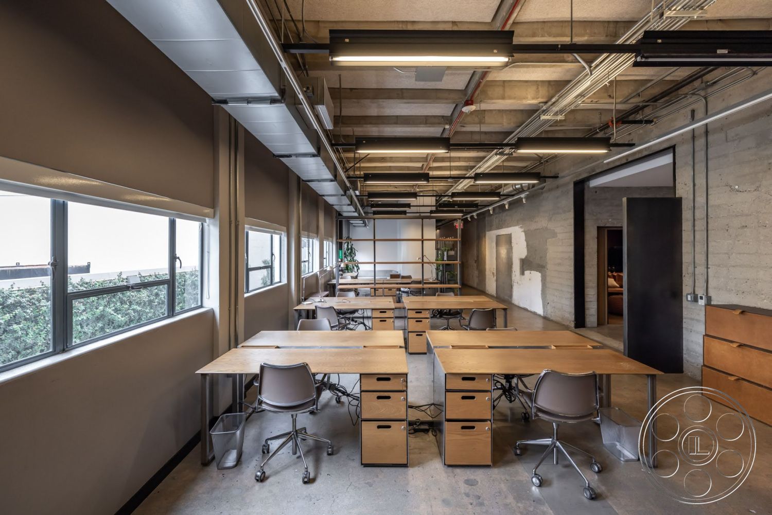 Sunset Campus - minimalist decor, large windows, polished concrete flooring, exposed concrete walls, open office layout, ergonomic office chairs, industrial style design, metal ceiling beams, wooden desks with storage drawers, overhead linear lighting fixtures