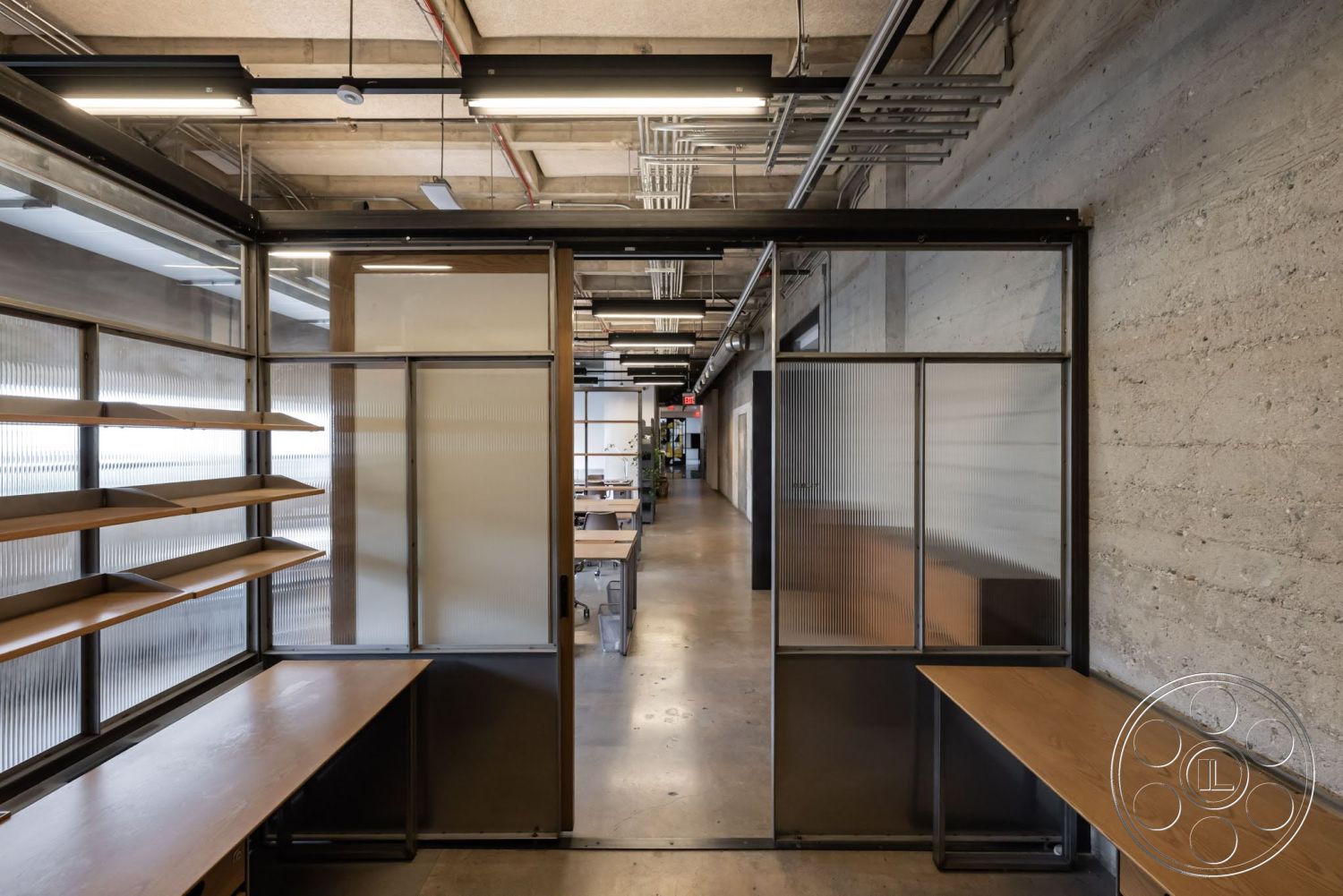 Sunset Campus - neutral color palette, minimalist aesthetic, polished concrete flooring, exposed concrete walls, exposed ductwork, wooden shelving units, glass partition walls, modern office design, track lighting fixtures, industrial style architecture, open workspace layout, steel framed doors