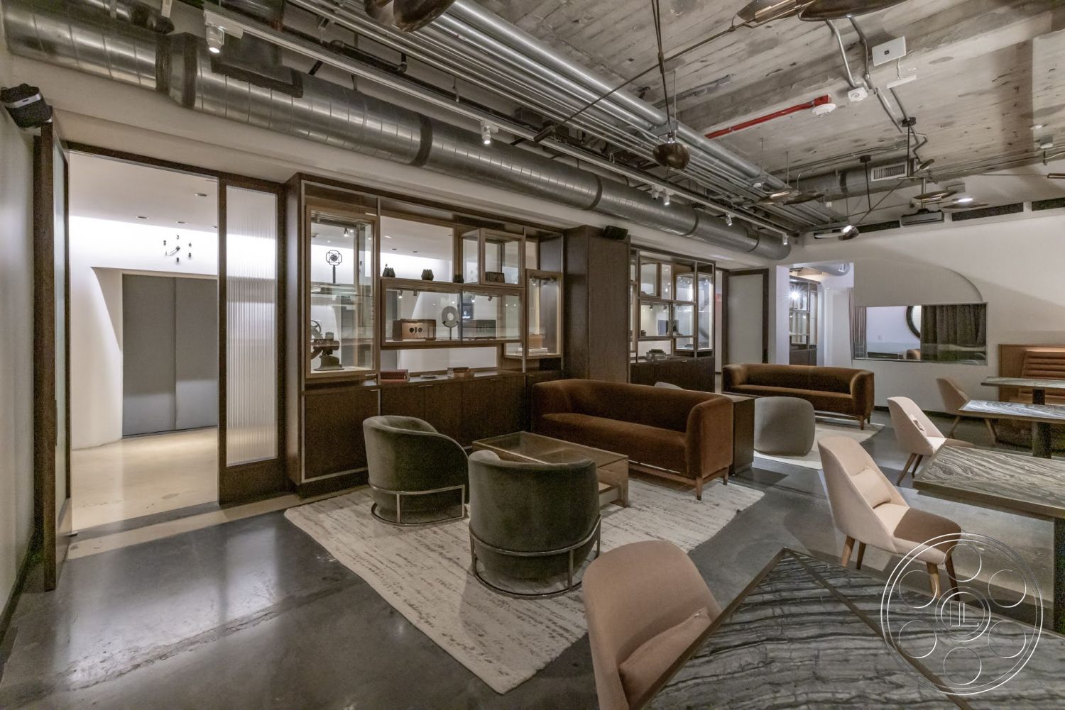 Sunset Campus - neutral color palette, polished concrete floors, suspended lighting fixtures, soft area rug, exposed ductwork, open floor plan layout, glass partition wall, wood paneling accent wall, modern lounge furniture, architectural ceiling beams, round upholstered chairs, rectangular dining tables