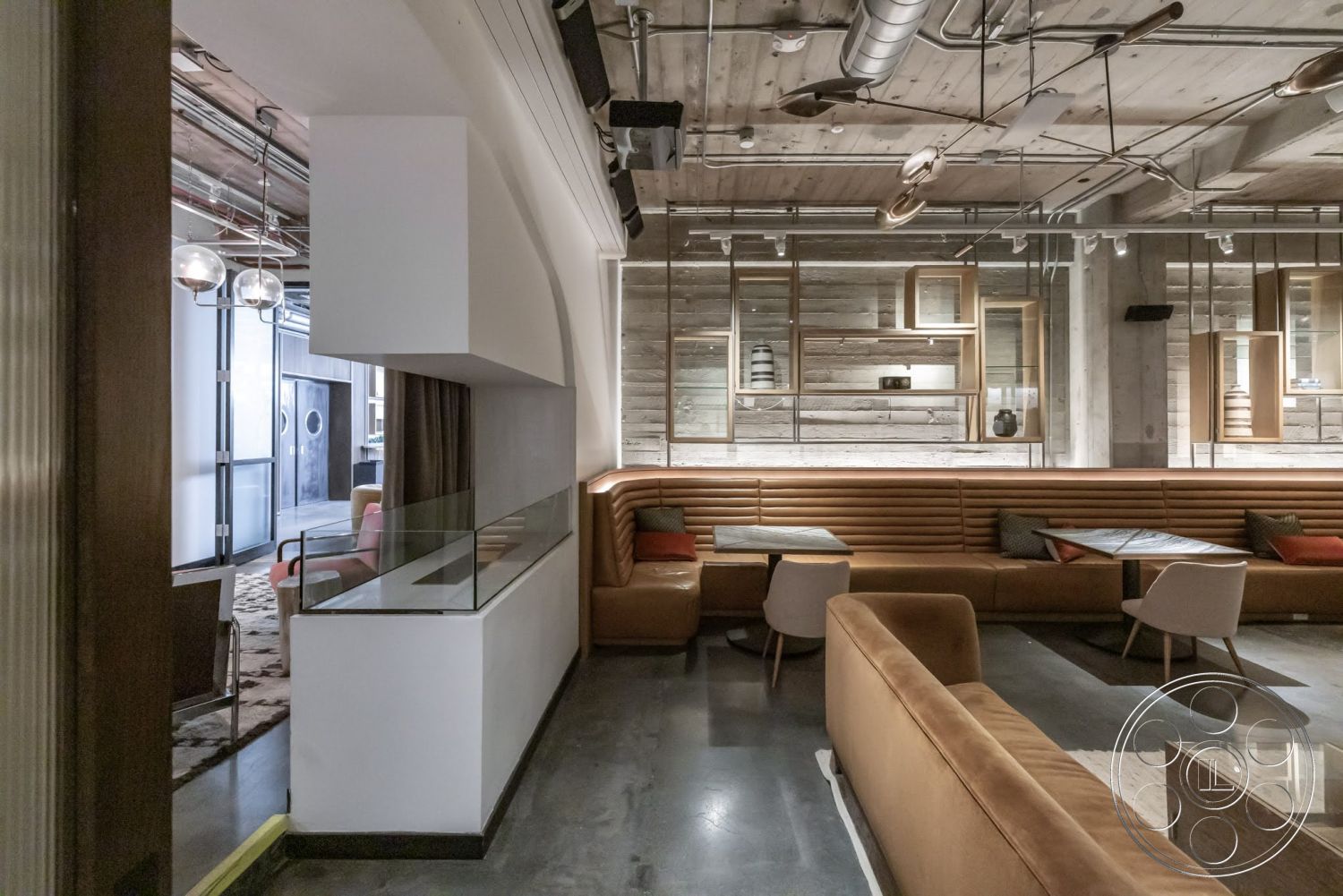 Sunset Campus - neutral color palette, open floor plan, concrete flooring, glass partition, striped area rug, industrial lighting fixtures, textured plaster walls, modern lounge area, exposed wood ceiling beams, wood panel accent wall, steel shelving units, upholstered leather seating, rectangular tables