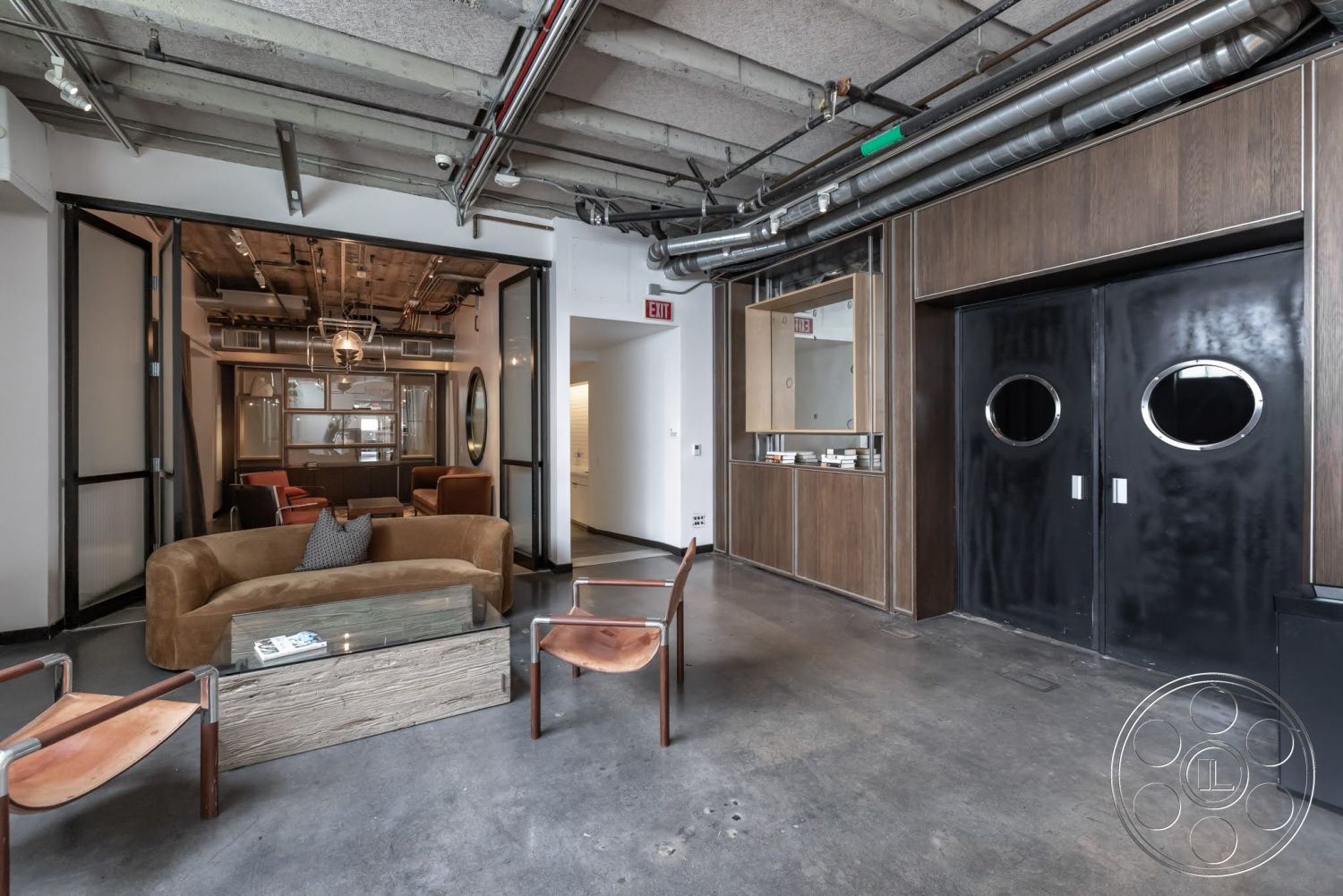 Sunset Campus - open floor plan, polished concrete flooring, glass coffee table, modern design elements, exposed concrete ceiling, leather armchairs, industrial light fixture, curved sofa, wood panel accent wall, urban loft setting, black double doors with circular windows
