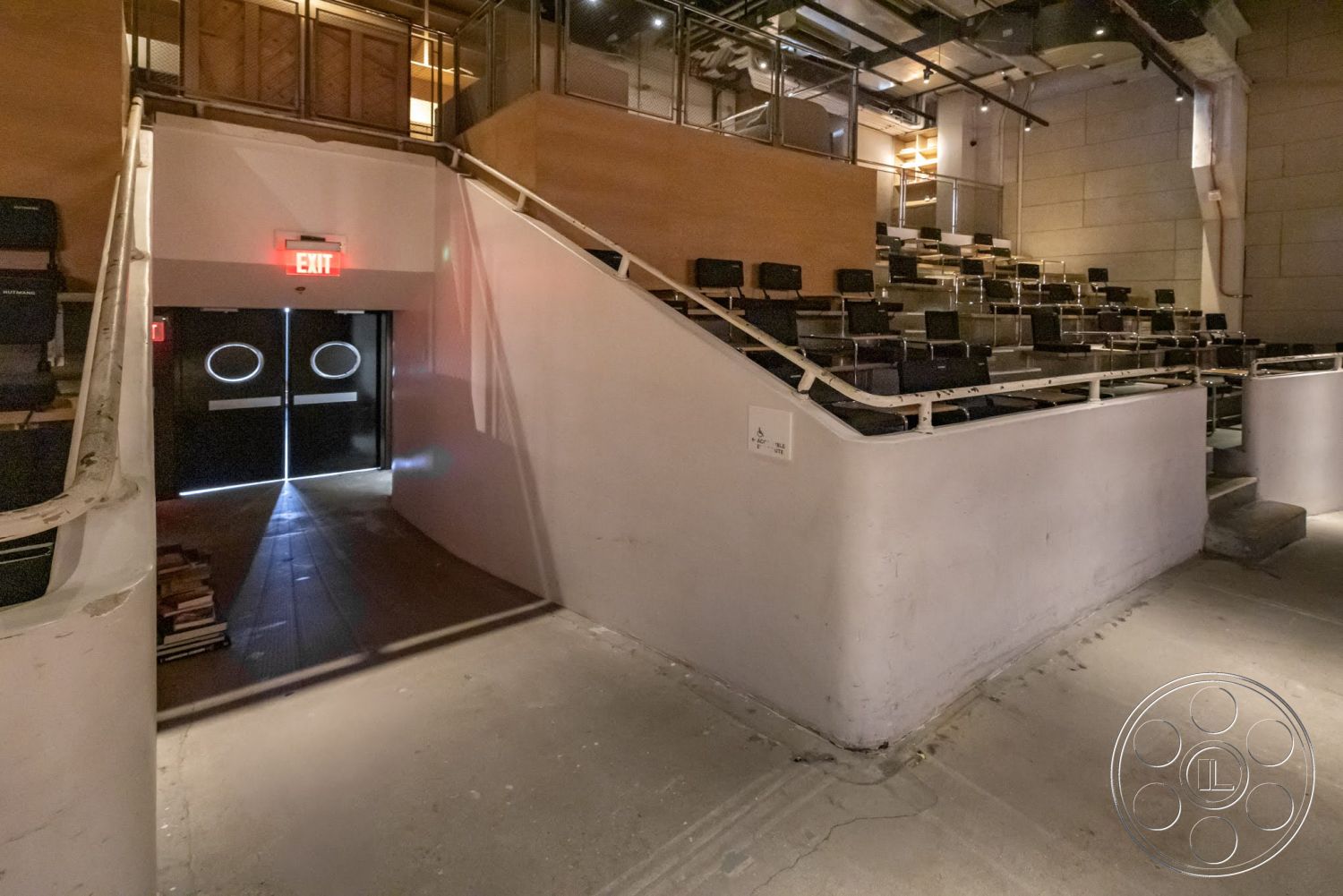 Sunset Campus - concrete flooring, modern architectural style, curved staircase, metal railing details, wood paneling accent wall, exposed cement walls, black theater seating