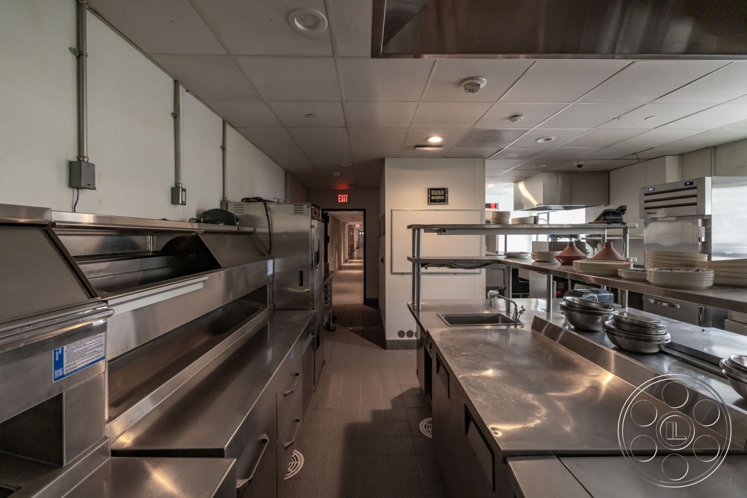 Sunset Campus - open kitchen layout, drop ceiling tiles, tile kitchen flooring, industrial kitchen design, stainless steel kitchen counters, stainless steel shelving units, commercial kitchen interior, ventilation hood, kitchen service counter, light fixture ceiling lights