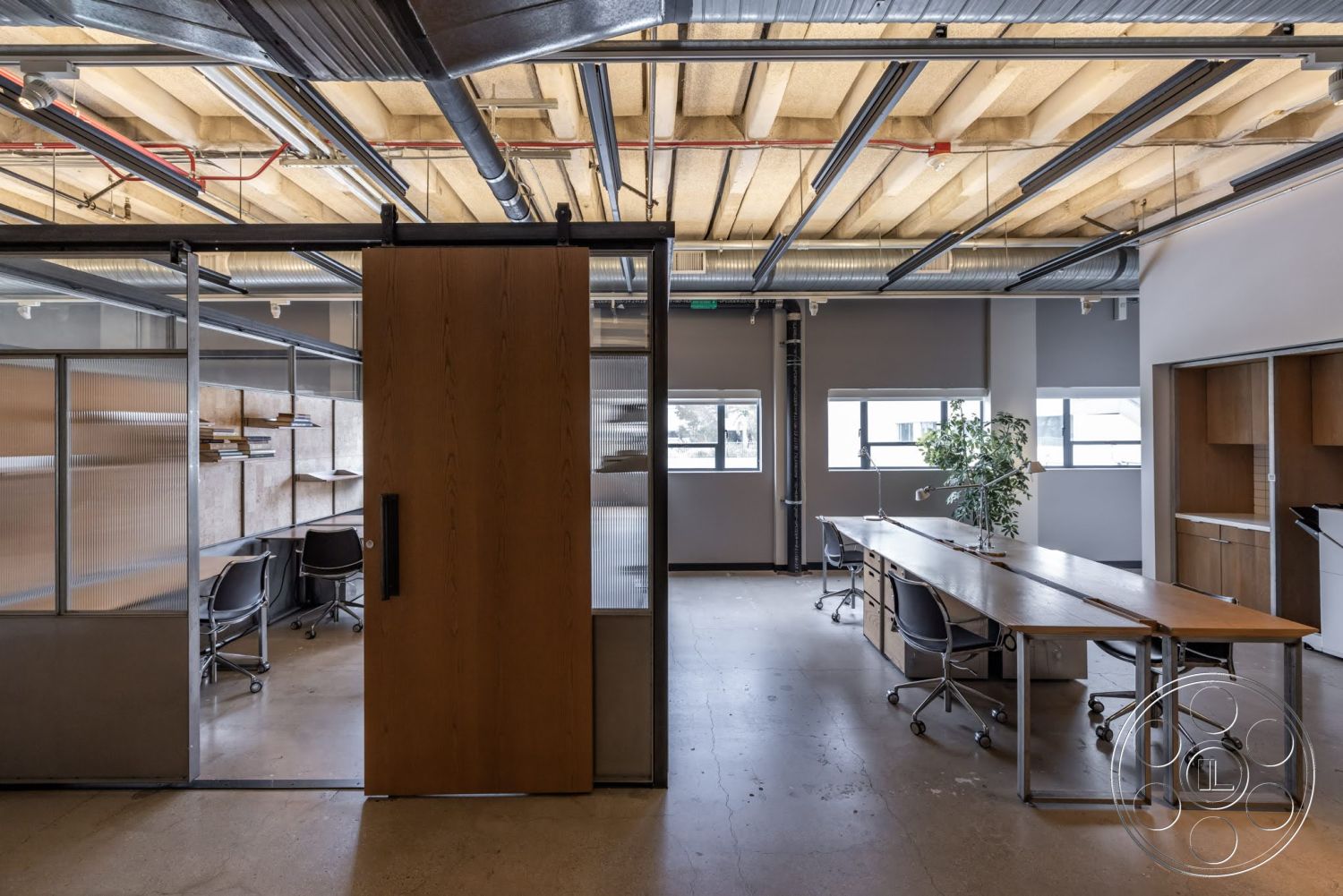 Sunset Campus - minimalist decor, concrete flooring, industrial style, collaborative workspace, natural light from windows, creative office environment, built-in cabinetry, exposed wood ceiling beams, glass partition walls, modern office design, steel structural beams, open workspace layout, plant accent, metal office furniture, wood sliding door
