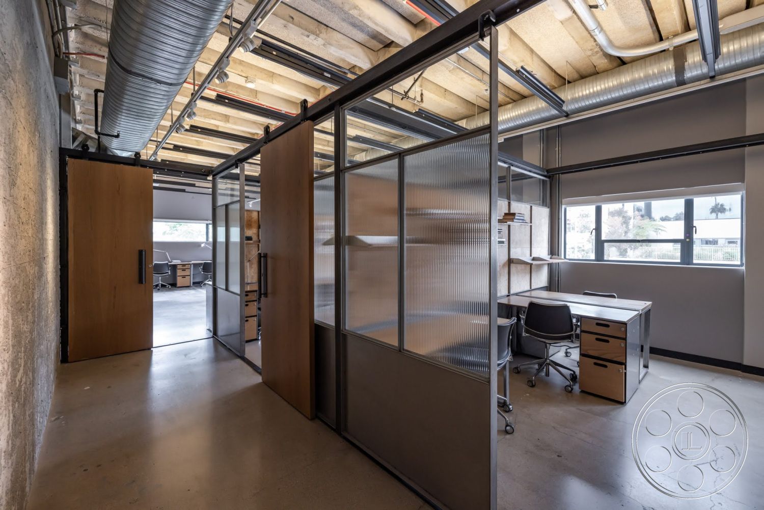 Sunset Campus - polished concrete flooring, exposed concrete walls, metal ductwork, glass partition walls, modern office space, metal ceiling beams, wood sliding doors