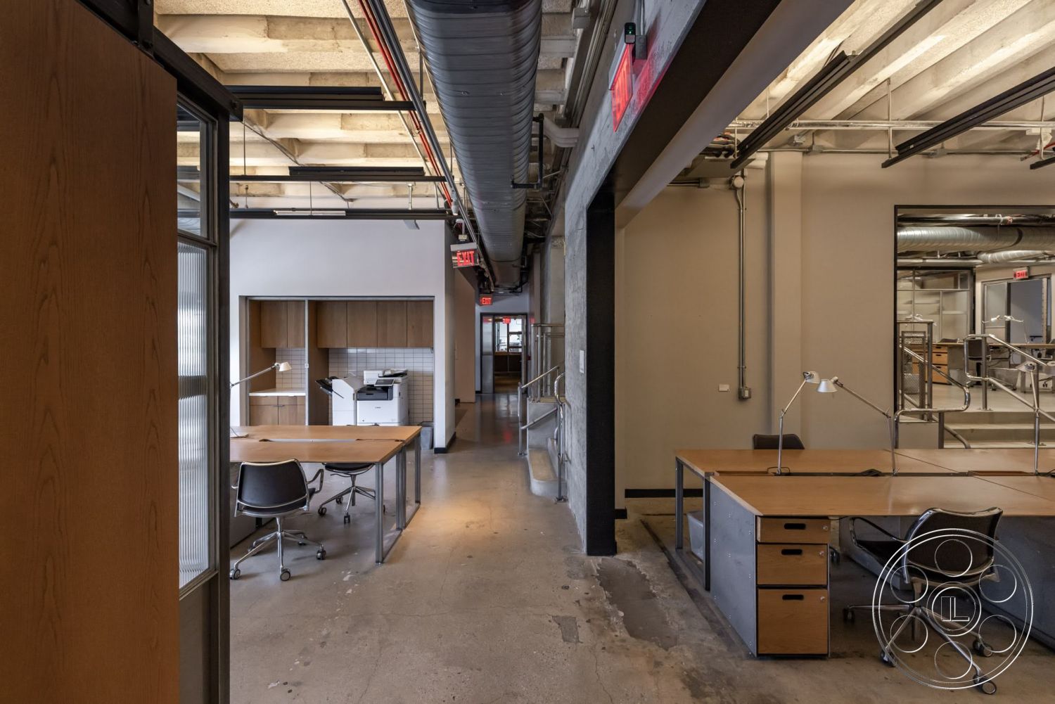 Sunset Campus - industrial style, collaborative workspace, floor-to-ceiling windows, exposed concrete floor, open office space, glass partition walls, modern office desks, wood panel cabinetry, metal ductwork ceiling