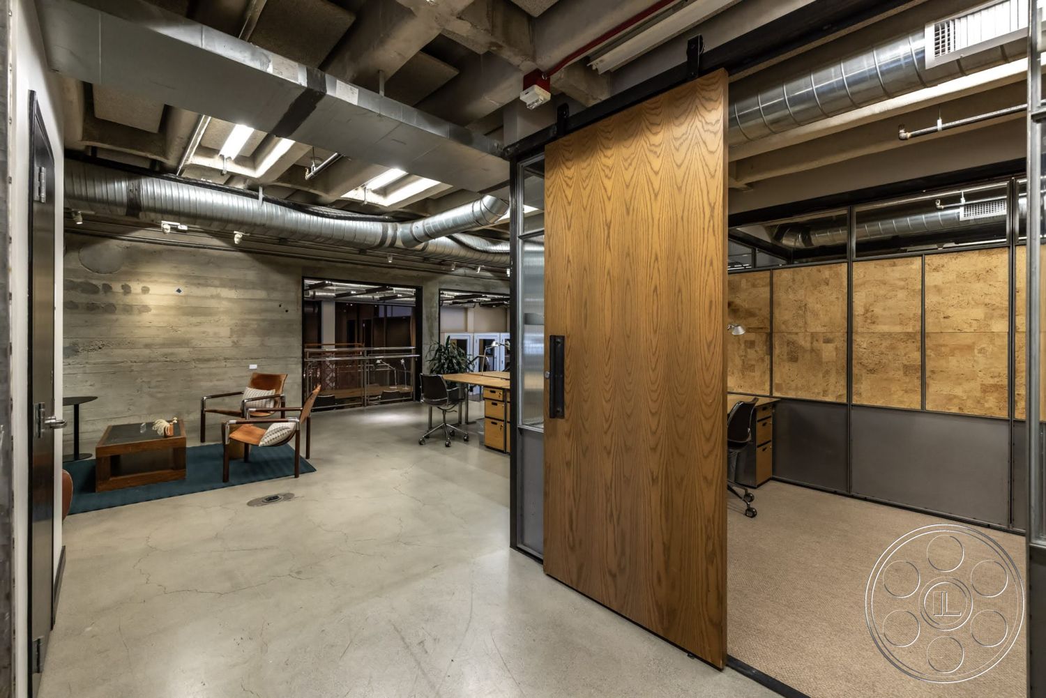 Sunset Campus - neutral color palette, concrete flooring, exposed concrete walls, task lighting, functional workspace, metal ductwork, wooden accent wall, open office layout, glass partition walls, modern office furniture, industrial-style ceiling, urban office interior, wood sliding door