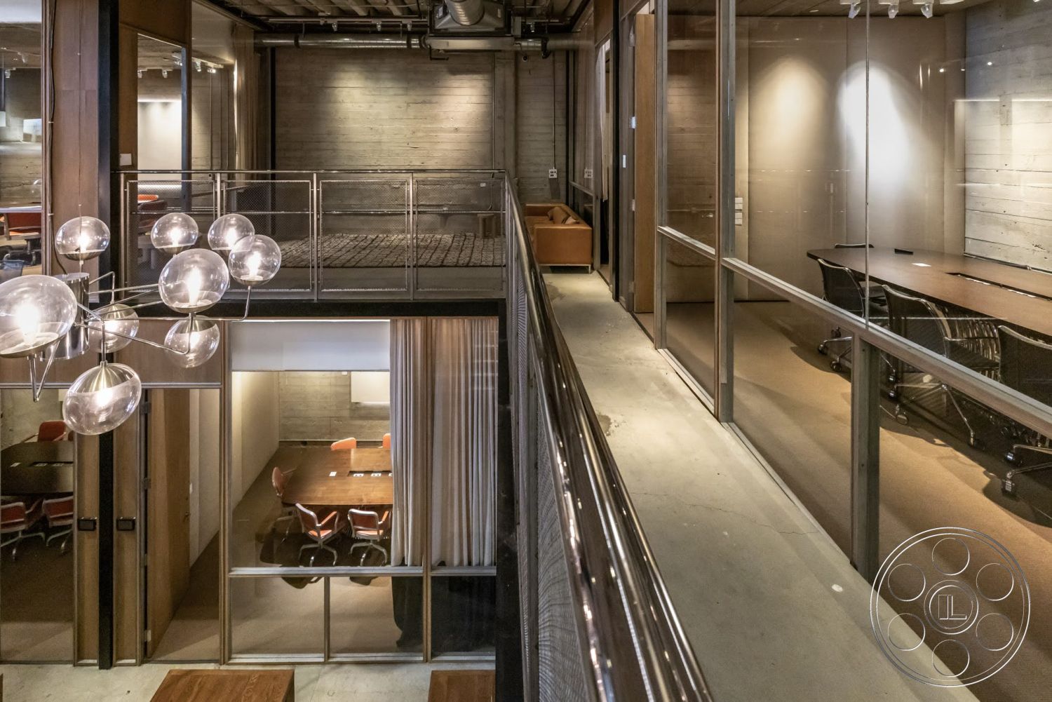 Sunset Campus - open floor plan, wood paneling, polished concrete flooring, exposed concrete walls, glass partition walls, modern chandelier lighting, industrial-style office, metal mesh balcony railing, two-story office space, conference room with glass walls