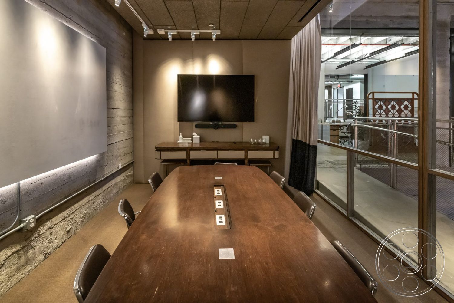 Sunset Campus - neutral color palette, exposed concrete walls, industrial lighting fixtures, carpeted flooring, flat-screen television, glass partition walls, modern office interior, wood conference table, wood paneling details, leather office chairs