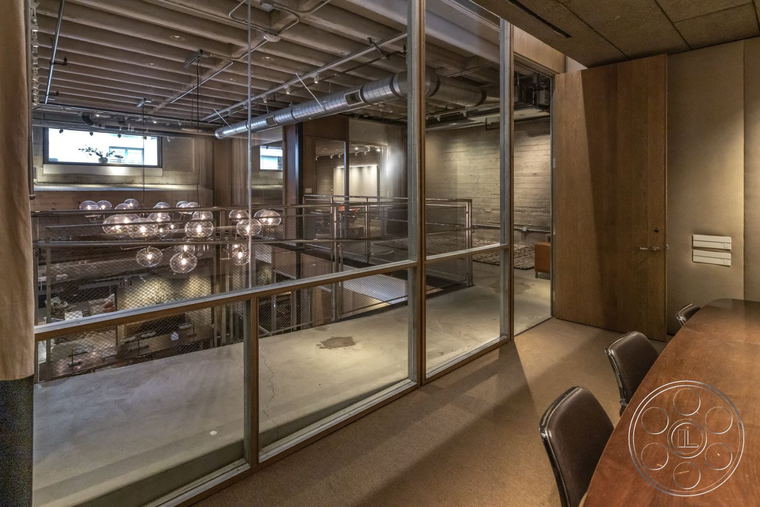 Sunset Campus - concrete flooring, open concept layout, natural light from windows, exposed concrete ceiling, glass partition walls, modern office space, industrial style architecture, metal railing balcony, wood paneling details, steel ductwork, pendant light fixtures, spacious loft design