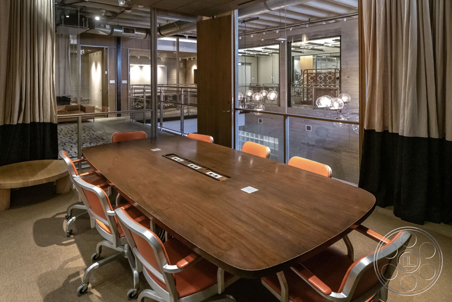 Sunset Campus - neutral color palette, floor-to-ceiling windows, industrial lighting fixtures, metal chairs, exposed ductwork, textured ceiling, open office layout, soft carpet flooring, modern office design, wood conference table, curtains with contrasting colors