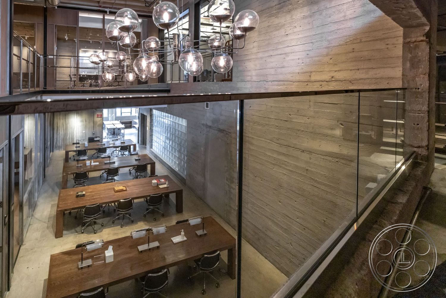 Sunset Campus - polished concrete flooring, concrete walls, modern workspace, industrial lighting fixtures, exposed concrete ceiling, steel railings, open office layout, glass partition walls, wood conference tables