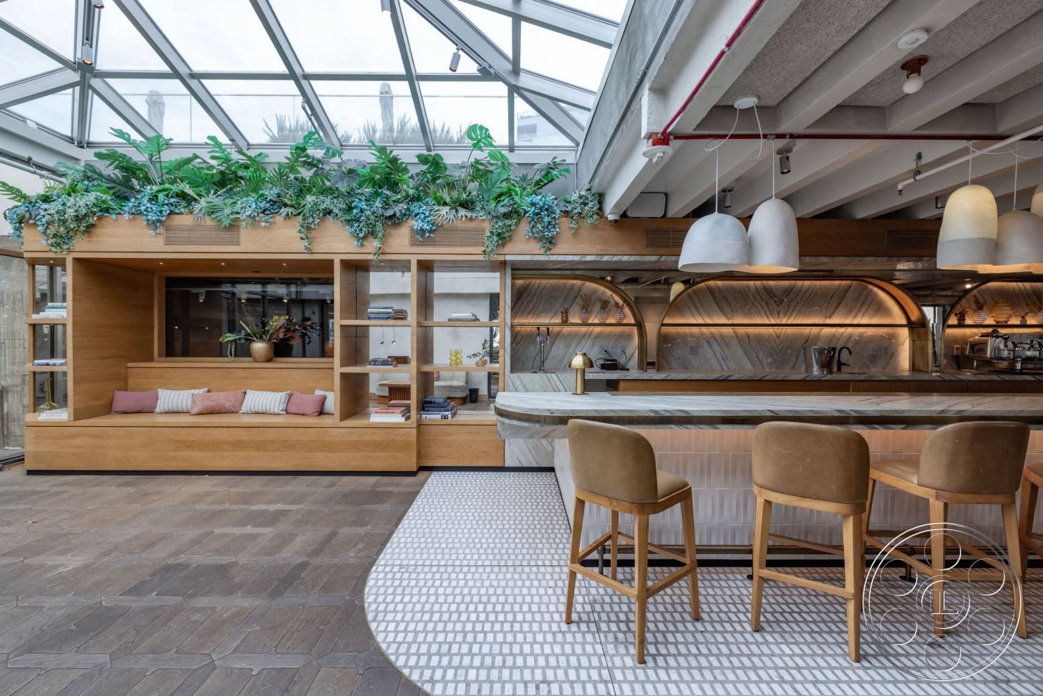 Sunset Campus - concrete ceiling, exposed ceiling beams, shelves with decor items, herringbone tile flooring, pendant lighting fixtures, built-in wooden seating area, marble bar countertop, wood feature wall, greenery planter