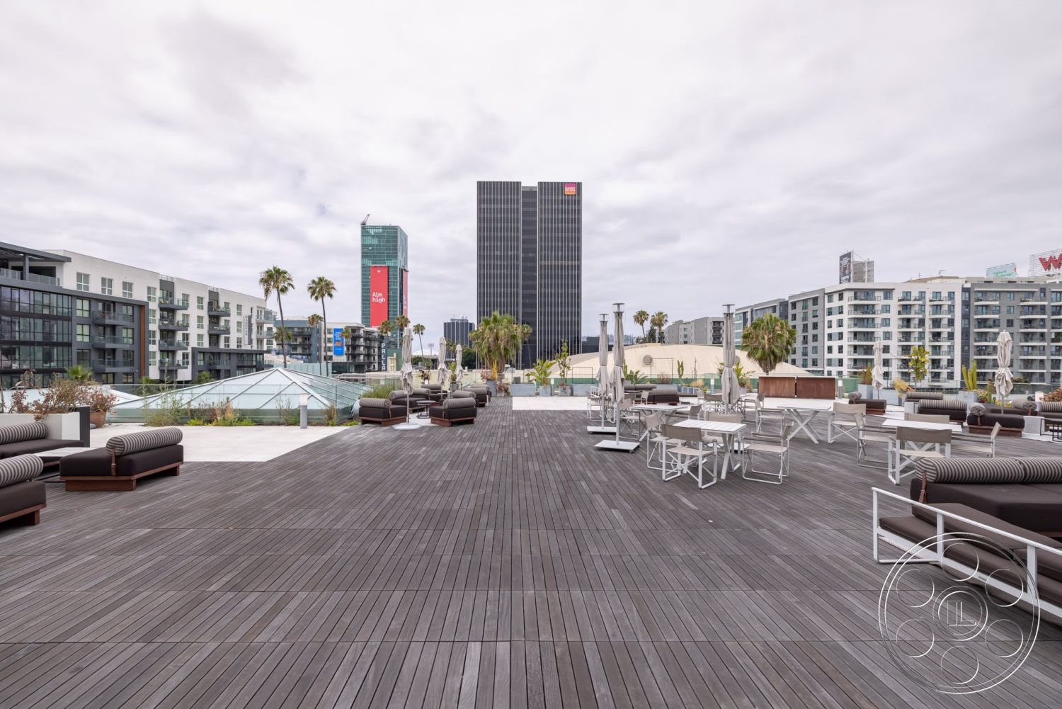 Sunset Campus - exterior, metal outdoor furniture, urban skyline view, modern outdoor lounge area, palm trees landscaping, composite wood decking, rectangular rooftop terrace, glass canopy structure