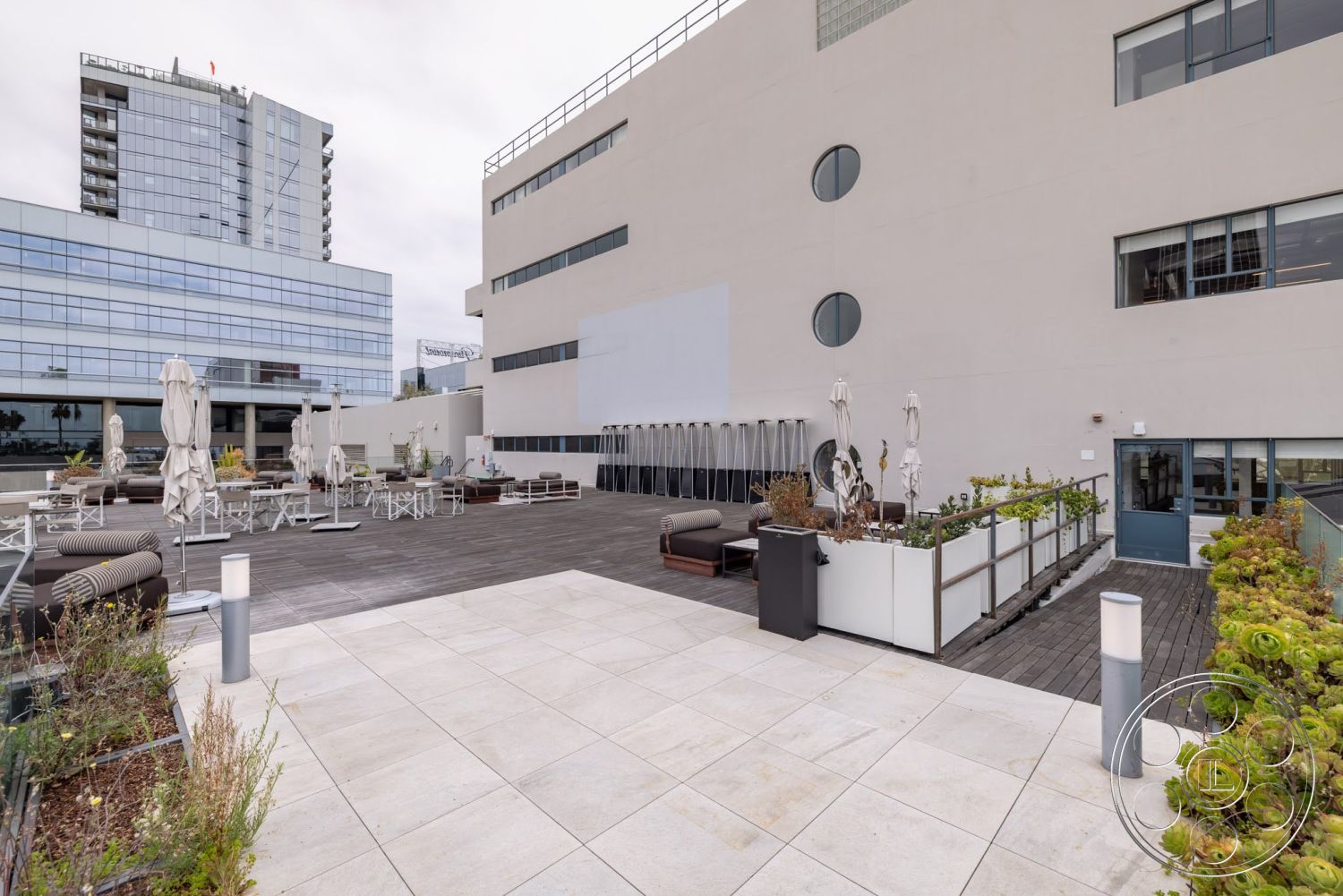 Sunset Campus - exterior, low-maintenance landscaping, glass railing, floor-to-ceiling windows, modern architectural style, city skyline view, canopy umbrellas, concrete patio flooring, aluminum outdoor furniture, urban rooftop terrace, wood deck surface, rectangular seating area, stainless steel planters