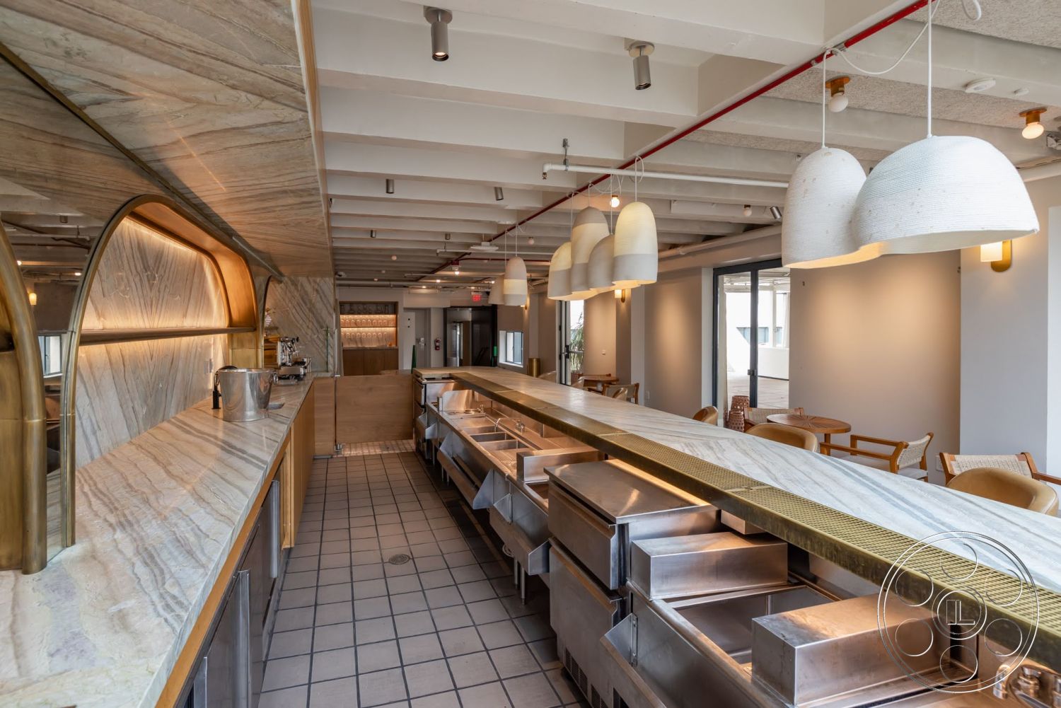 Sunset Campus - open floor plan, marble countertop, wooden dining chairs, stainless steel kitchen appliances, white tile flooring, industrial-style ceiling beams, modern restaurant design, oval pendant lighting, arched bar area