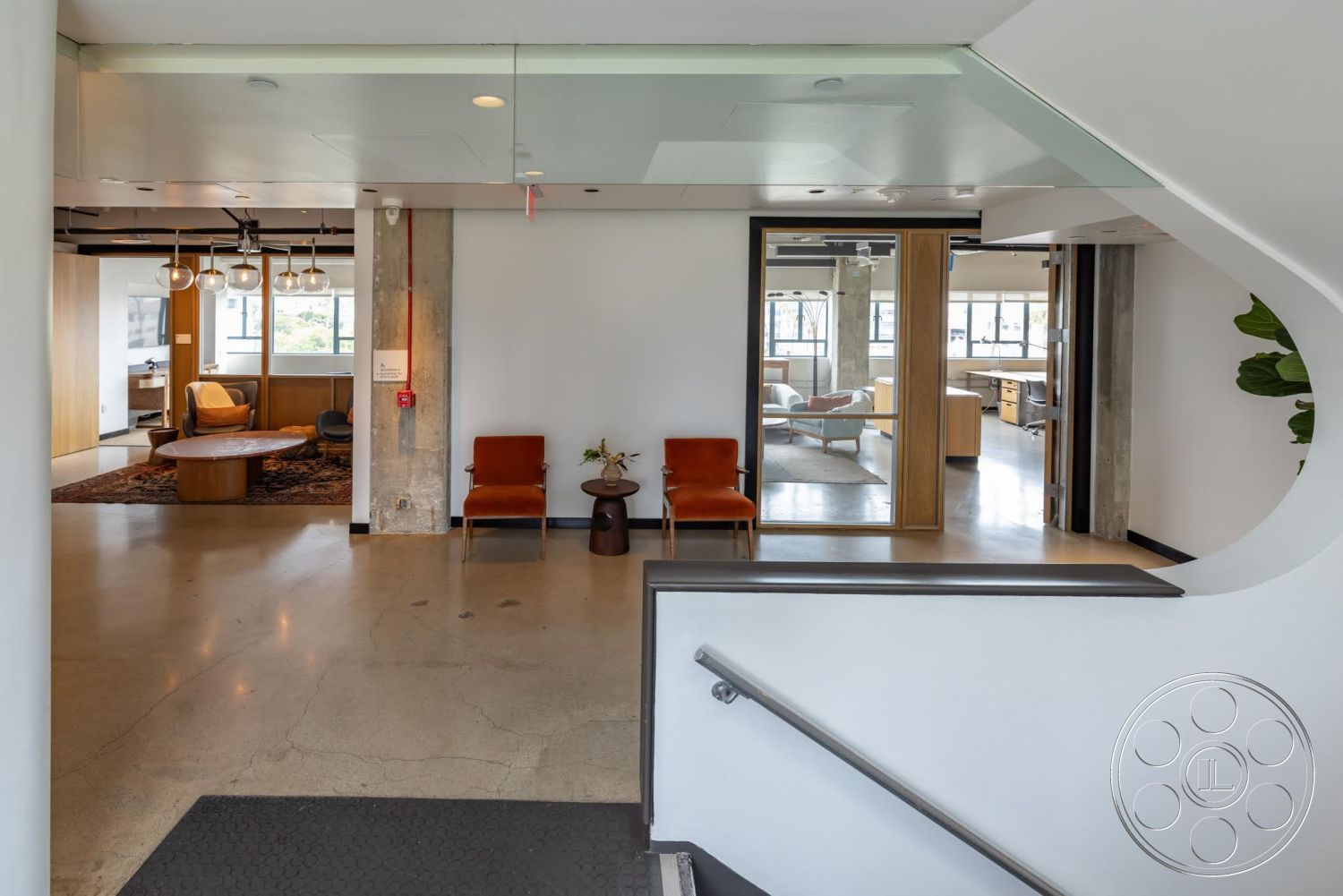 Sunset Campus - polished concrete flooring, modern pendant lighting, exposed concrete walls, floor-to-ceiling windows, circular coffee table, wood accent walls, curved staircase, glass partition walls, white painted walls, open concept living area, mid-century modern chairs