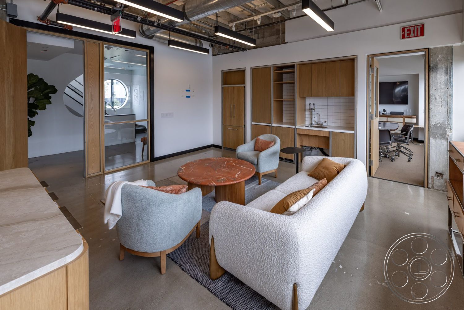 Sunset Campus - minimalist decor, neutral color palette, natural light, polished concrete flooring, light wood cabinetry, functional workspace, floor-to-ceiling windows, contemporary design elements, round marble coffee table, open office layout, glass partition walls, exposed ductwork ceiling, curved accent chairs, modern upholstered sofa, white ceramic tile backsplash, designed for collaboration, office kitchenette