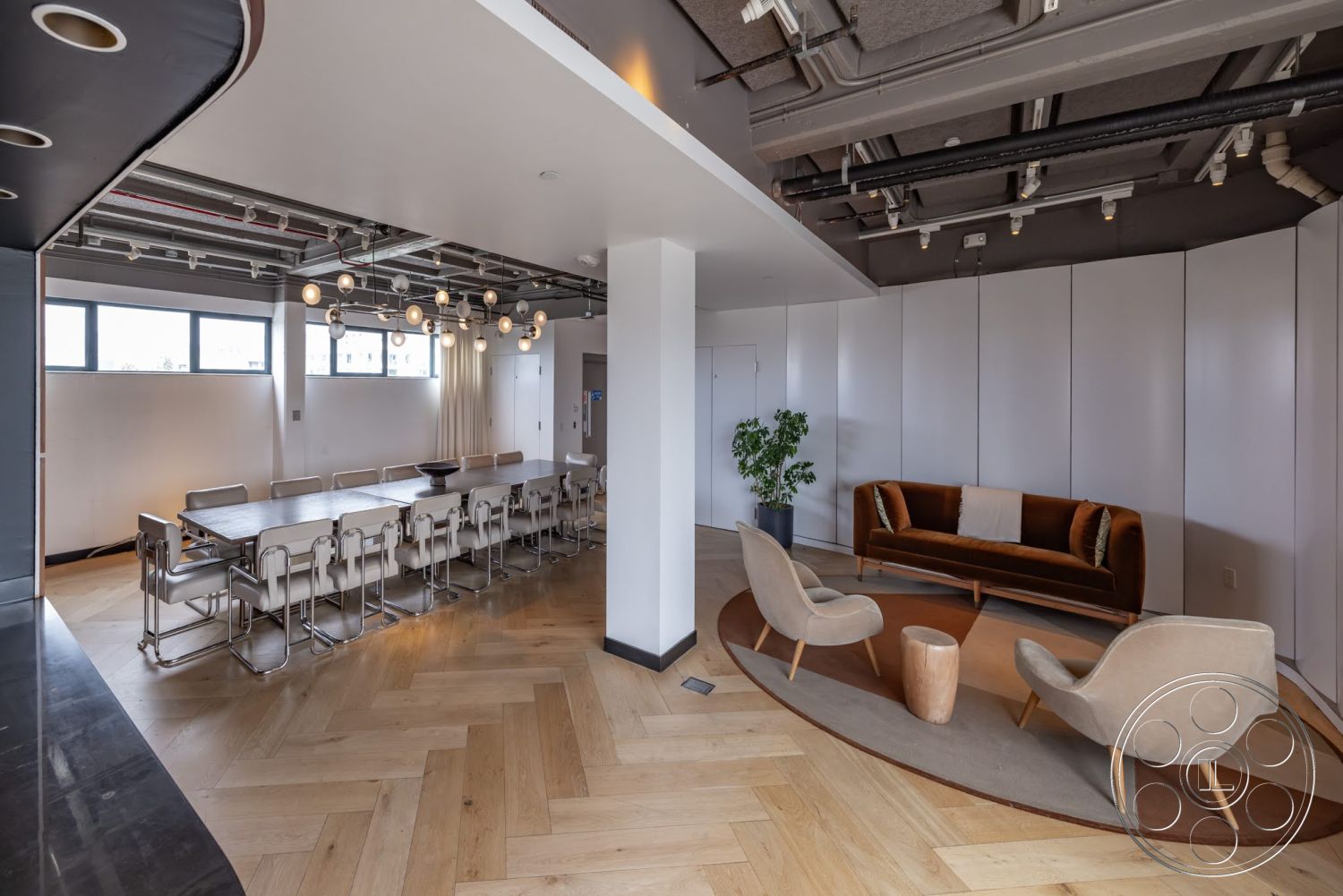 Sunset Campus - neutral color palette, minimalist design elements, floor-to-ceiling windows, exposed ceiling beams, round area rug, contemporary lighting fixtures, white painted walls, herringbone hardwood flooring, potted indoor plant, modular conference table, upholstered seating chairs, accent sofa with velvet upholstery