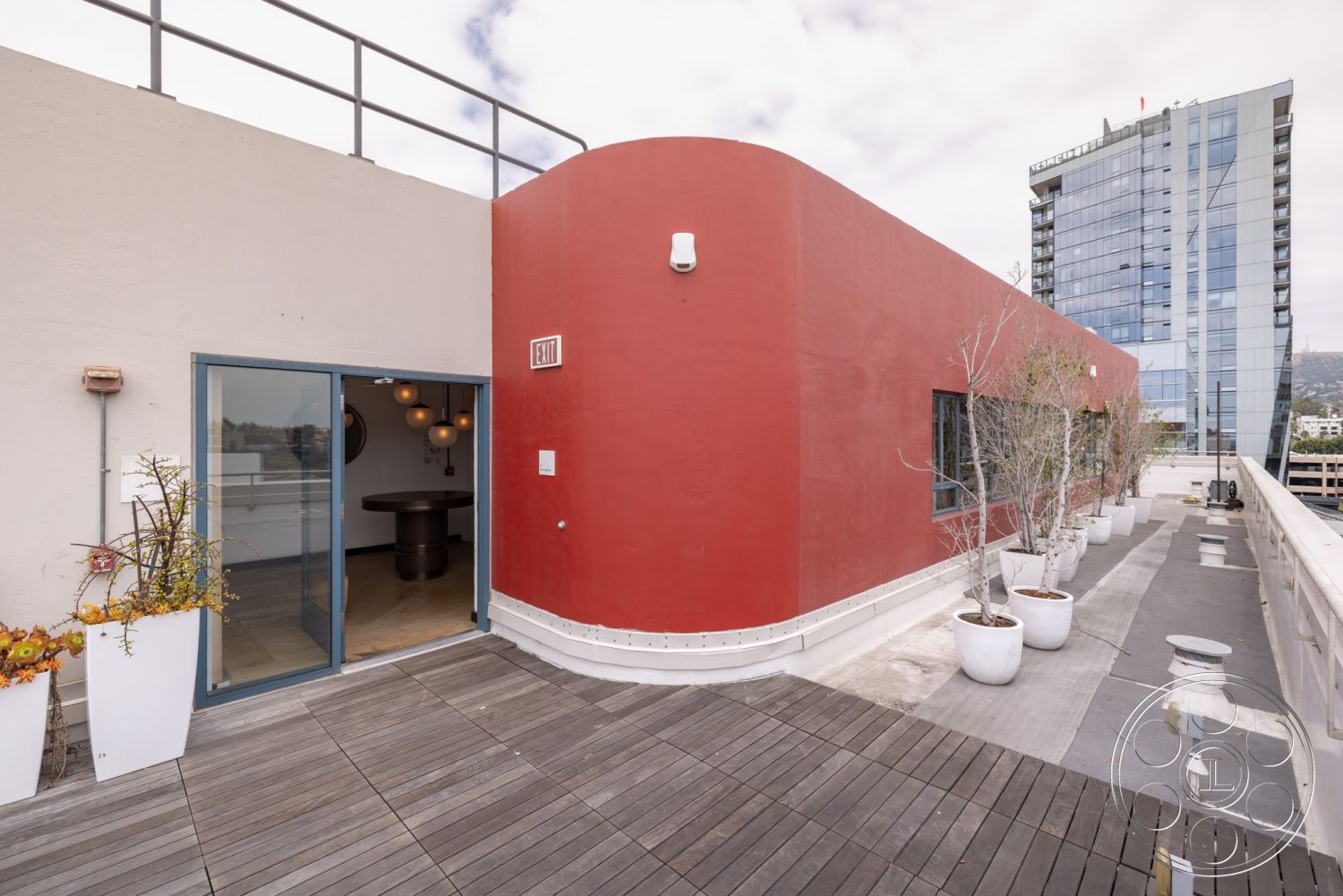 Sunset Campus - glass sliding doors, contemporary design elements, modern architectural style, urban skyline view, wooden deck flooring, exterior rooftop terrace, red plastered walls, white planters with greenery