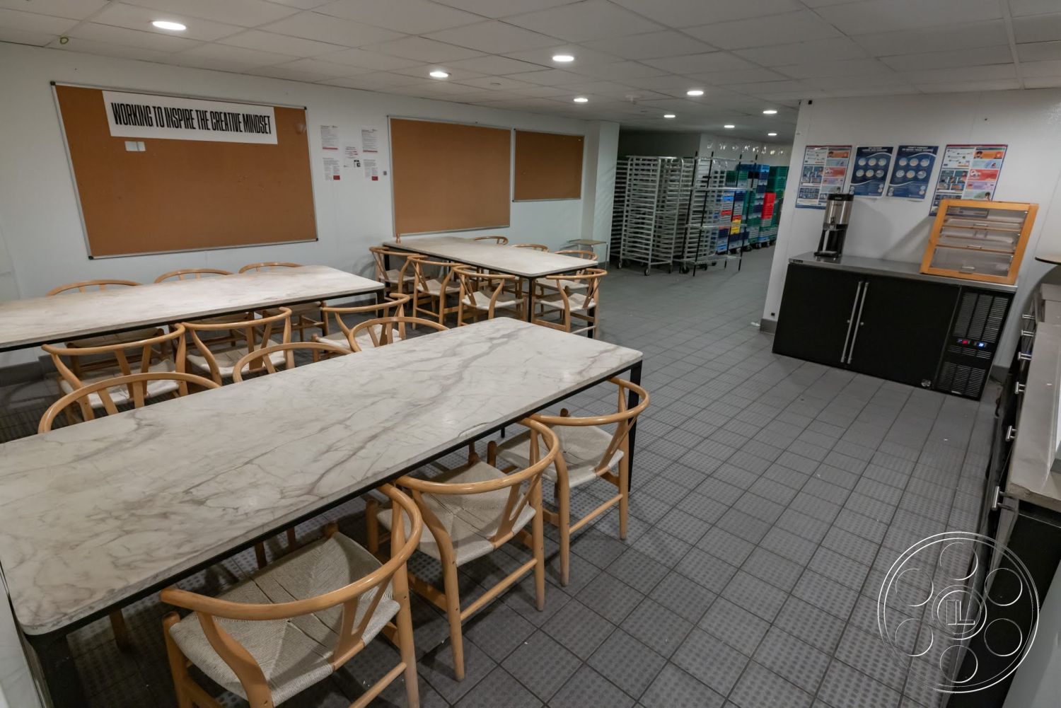 Sunset Campus - black cabinetry, gray tile flooring, wooden dining chairs, exposed ceiling lights, bulletin board wall, commercial kitchen area, marble dining table surface