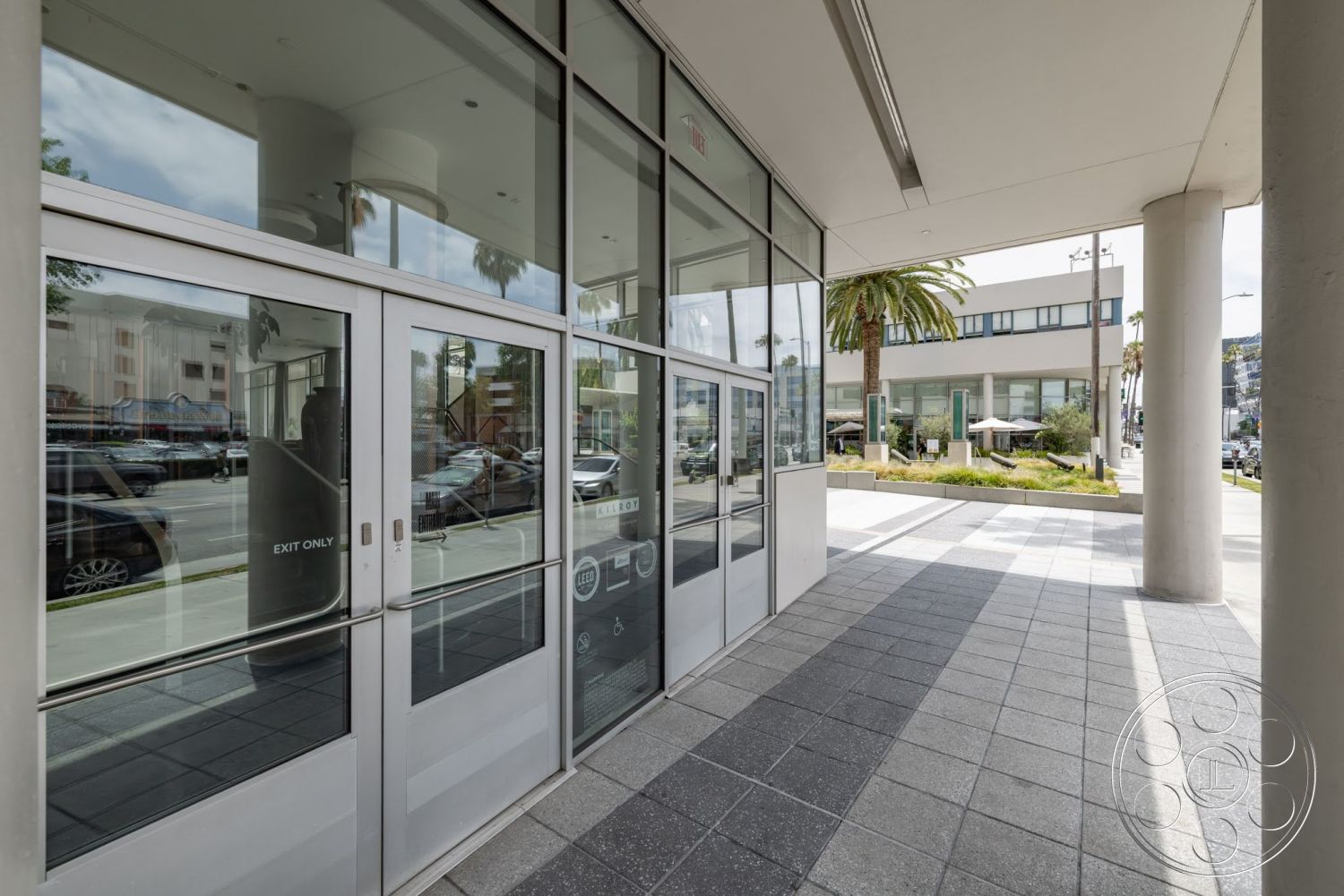 Sunset Campus - exterior, palm trees, modern architectural style, landscaped garden area, glass storefront windows, porcelain tile flooring, paved pedestrian walkway, metal framed doors, concrete building columns