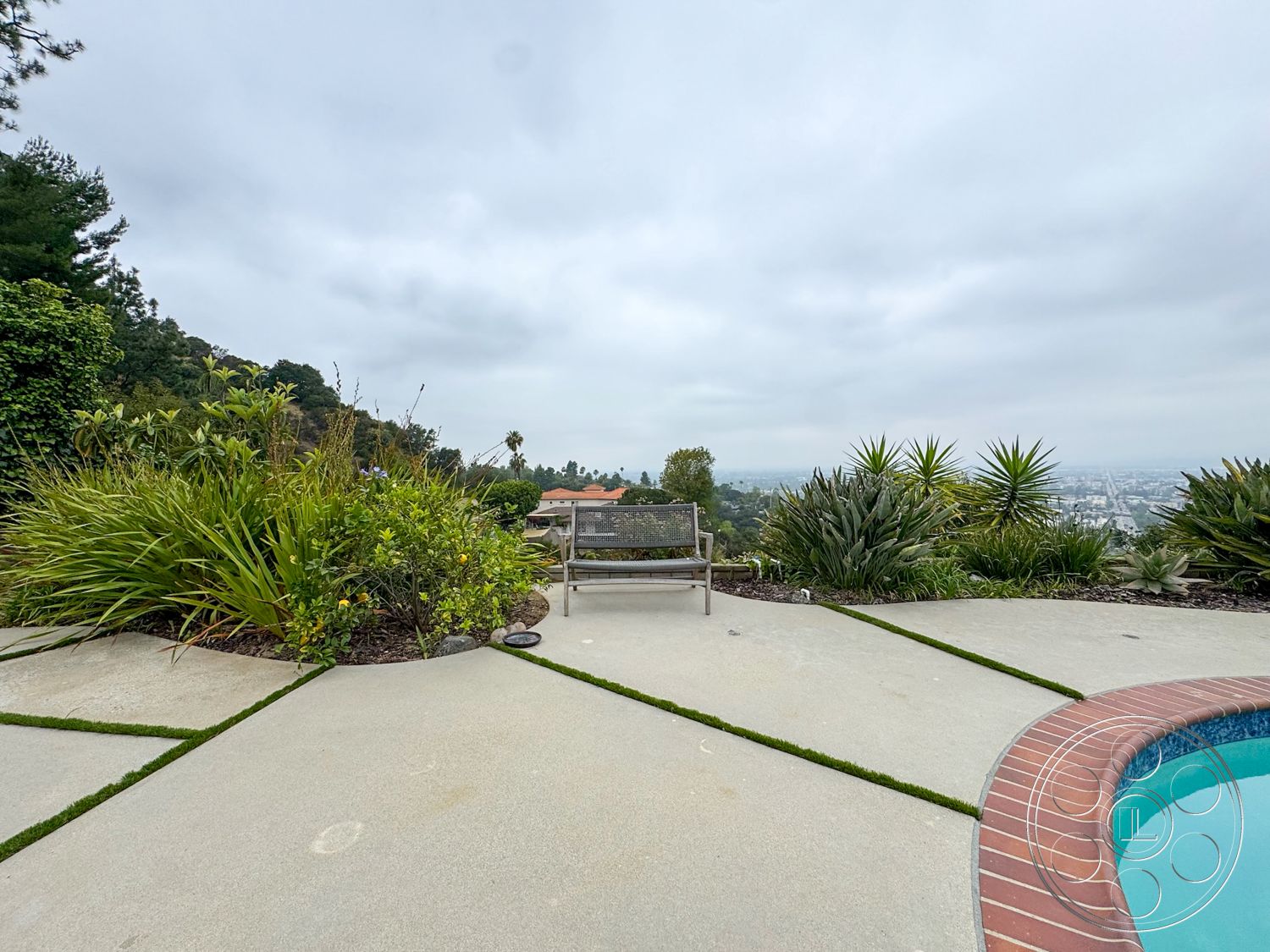Once Upon Hollywood - exterior, lush landscaping, metal bench, rectangular pool, distant city skyline, concrete patio flooring, native plant garden, brick pool border, open hillside view