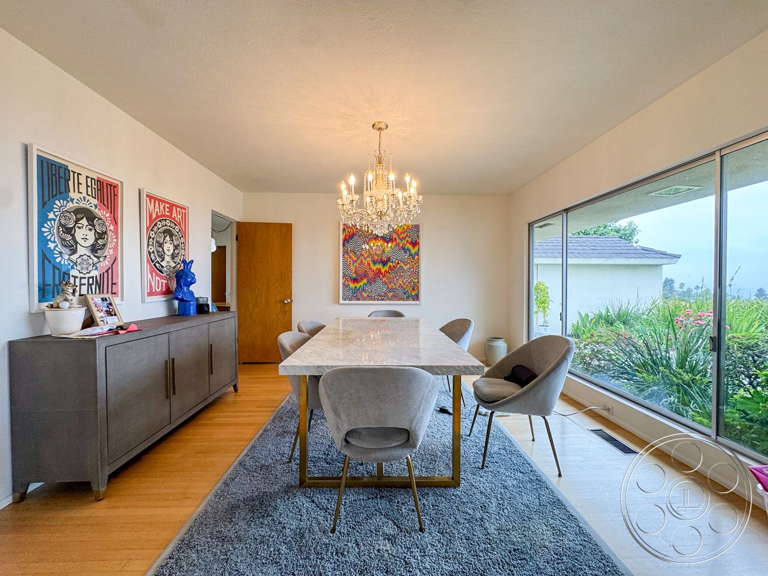 Once Upon Hollywood - textured area rug, upholstered dining chairs, floor-to-ceiling windows, framed art on walls, marble dining table, interior dining room, natural light illumination, chandelier lighting fixture, modern decor style, bamboo hardwood flooring, metallic gold table legs, plaid accent wall, visible greenery outside
