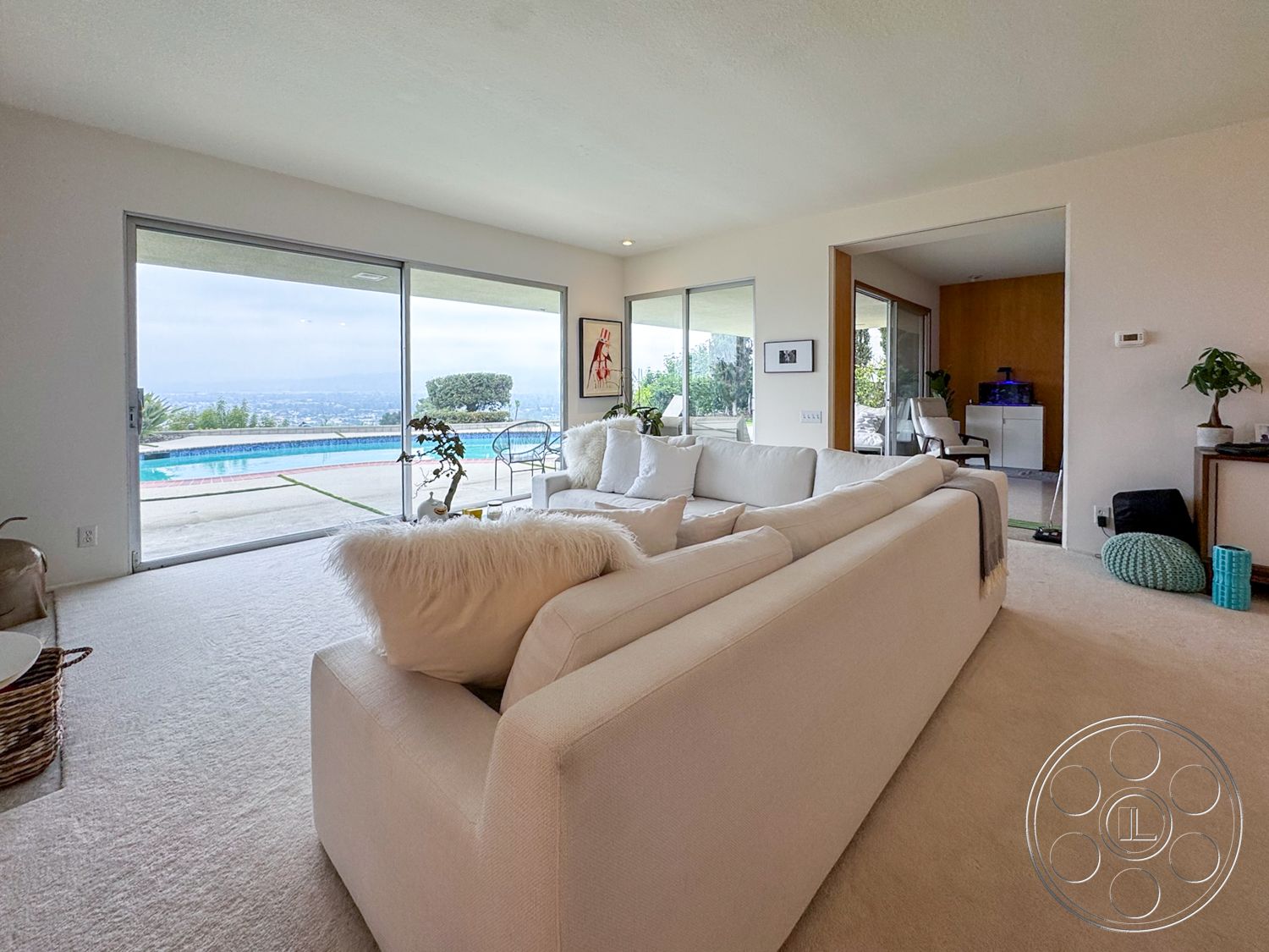 Once Upon Hollywood - neutral color palette, minimalist design, indoor plants, open floor plan, cozy seating area, modern architectural style, mountain view, light wood paneling, natural light illumination, floor-to-ceiling glass sliding doors, concrete pool patio, plush carpet living room flooring, white sectional sofa upholstery