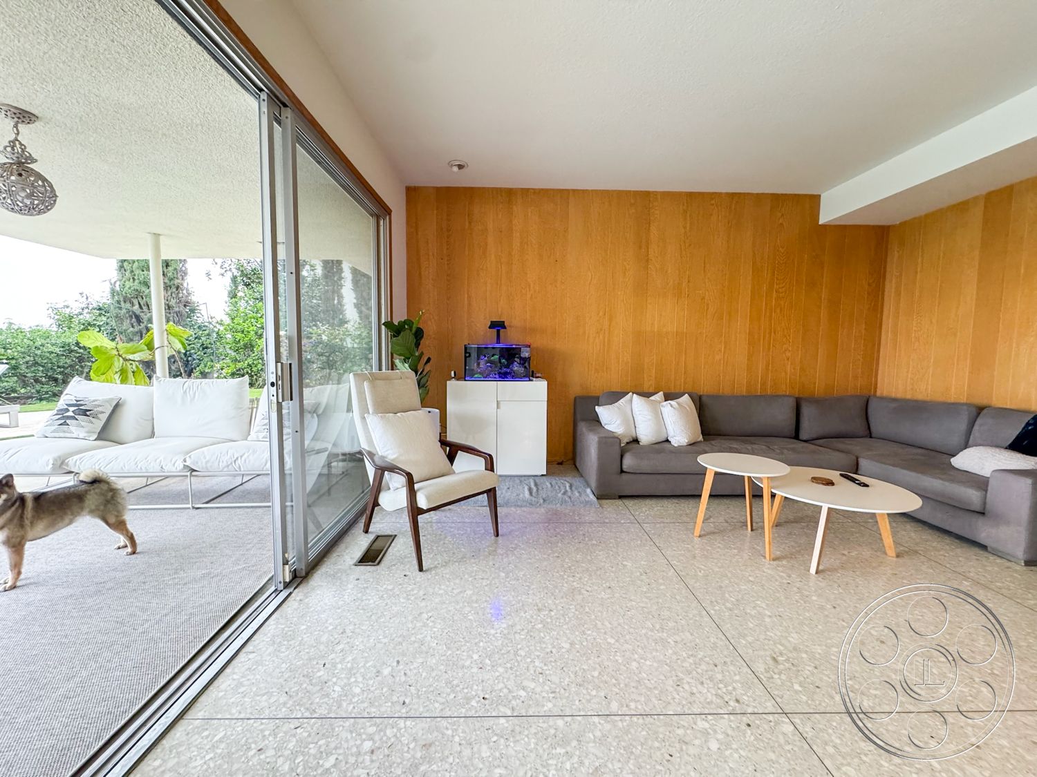 Once Upon Hollywood - terrazzo flooring, indoor plants, glass sliding doors, open-concept living space, minimalist coffee table, modern sectional sofa, wood panel accent wall, contemporary upholstered armchair