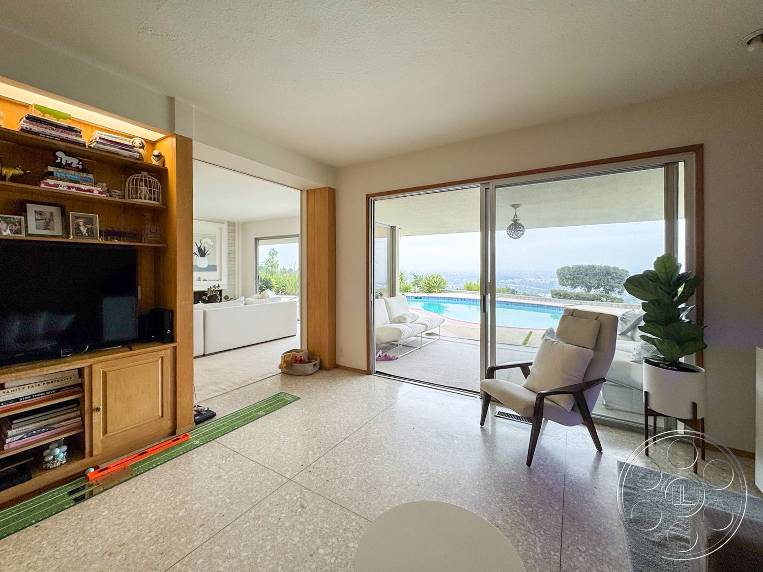Once Upon Hollywood - terrazzo flooring, open floor plan, glass sliding doors, vaulted ceiling, framed wall art, contemporary living room, indoor plant decor, modern seating arrangement, interior lighting fixtures, pool view from living area, wooden built-in cabinets, exposed ceiling texture, light-toned neutral walls