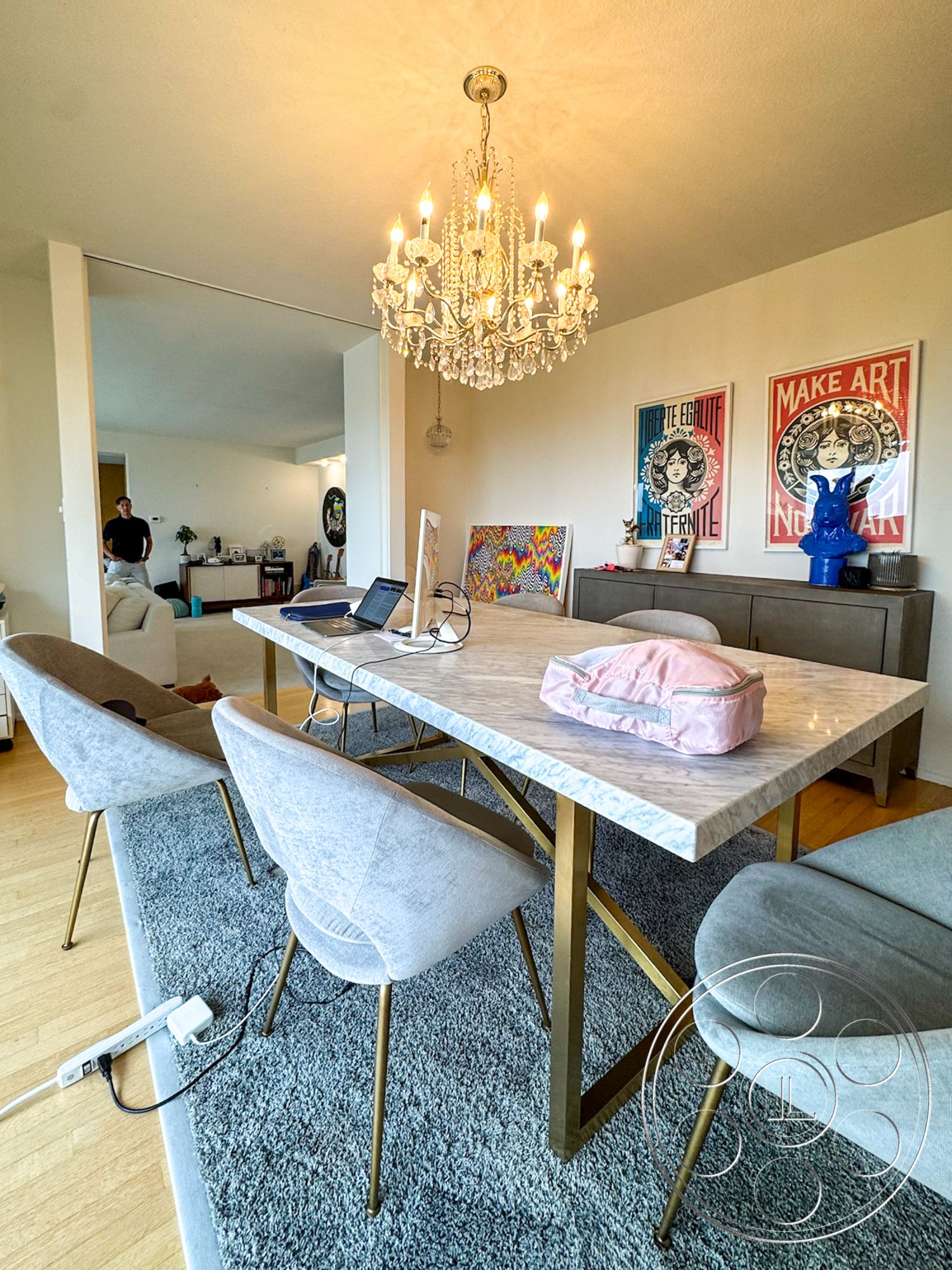 Once Upon Hollywood - modern design, light wood flooring, area rug, open concept layout, decorative wall art, marble dining table, chandelier with crystal accents, brass table legs, gray upholstered dining chairs
