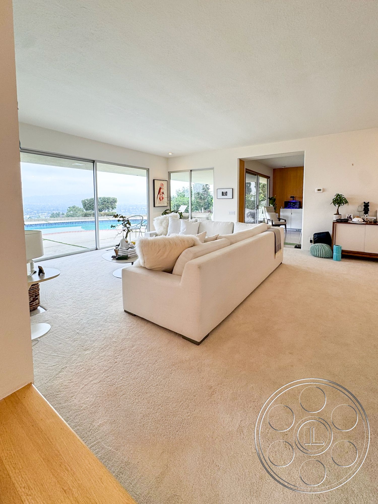 Once Upon Hollywood - minimalist decor, natural light, contemporary furniture, open floor plan, framed artwork, floor-to-ceiling windows, vaulted ceiling, textured plaster walls, carpet living room flooring