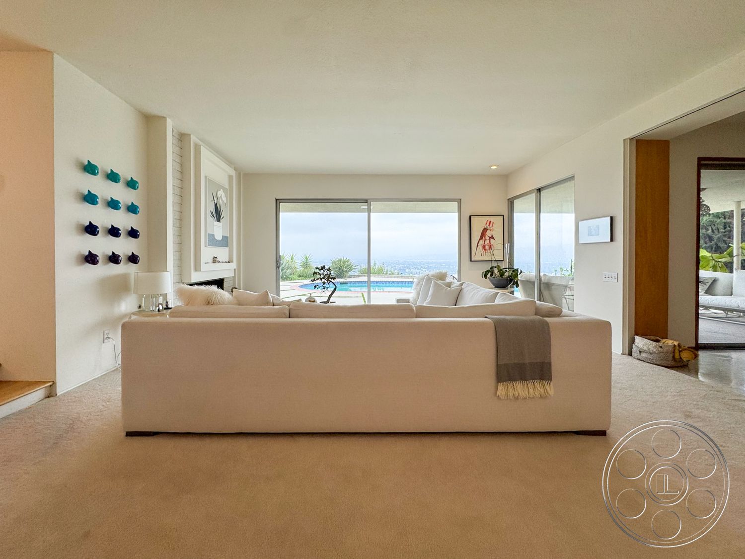 Once Upon Hollywood - minimalist decor, neutral color palette, glass sliding doors, contemporary furnishings, vaulted ceiling, open concept living space, white painted walls, modern sectional sofa, indoor plant accents, plush carpet flooring, large windows with scenic views, horizontal art wall display, sliding door access to pool area