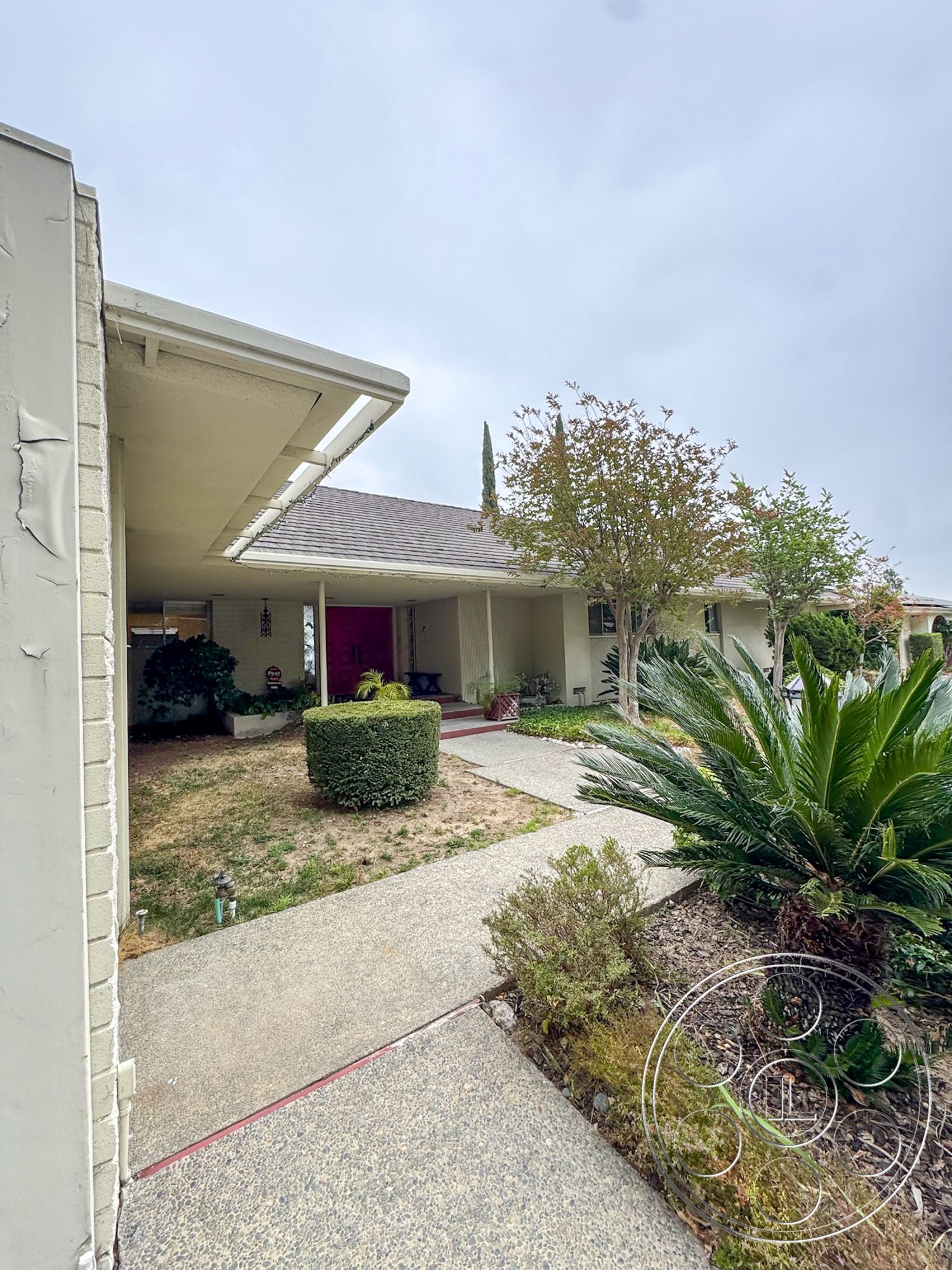 Once Upon Hollywood - exterior, asphalt shingle roof, palm trees, landscaped front yard, grass lawn, concrete walkway, stucco walls, stone accents, red front door, rounded hedges, decorative front porch, flat patio roof