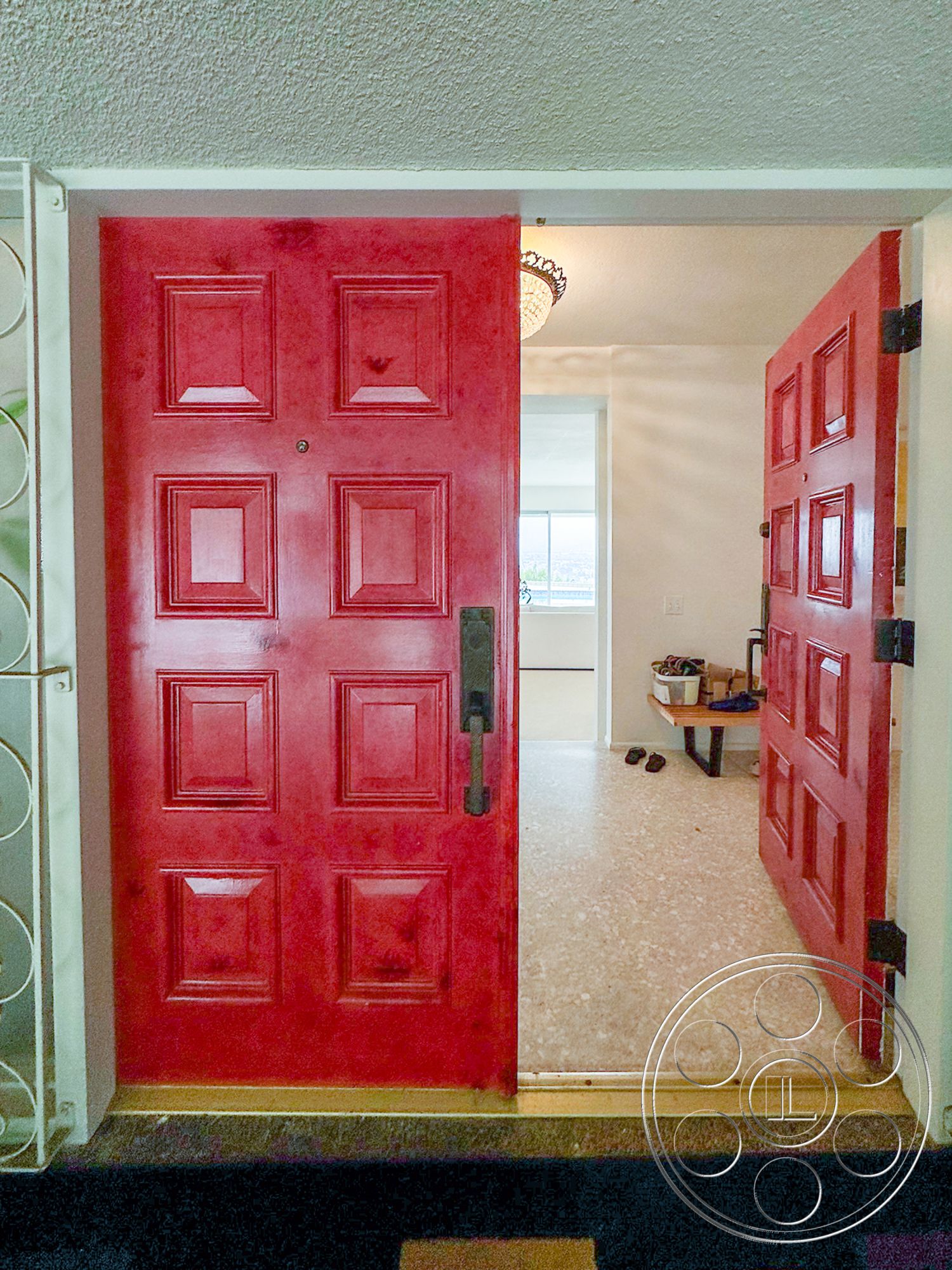 Once Upon Hollywood - minimalist decor, open floor plan, textured ceiling, hard surface flooring, interior entryway, entrance hallway, chandelier lighting fixture, red double entry doors, panelled door design