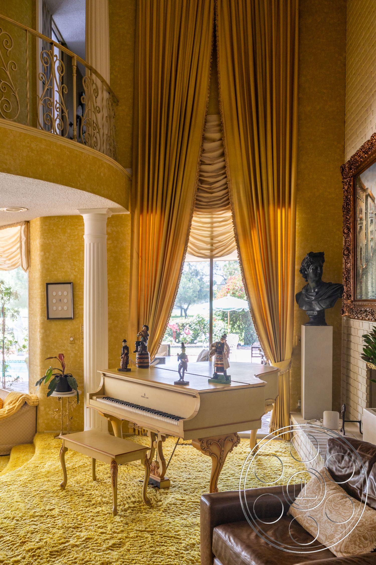 Euphoria - floor-to-ceiling windows, soft lighting fixtures, textured yellow walls, exposed brick fireplace surround, open living space layout, view of outdoor garden, plush shag carpet flooring, grand piano with ornate legs, luxurious drapery with pleats, wooden framed art piece, decorative bust sculpture, wooden plant stand, accent pillows on leather sofa, intricate wrought iron balcony railing, stylized figurine decorations