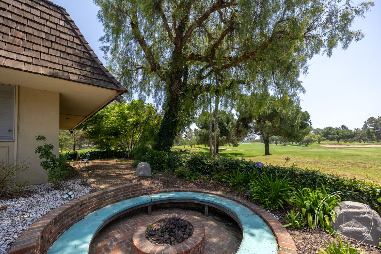 Euphoria - exterior, natural stone accents, asphalt shingle roof, lawn area, gravel ground cover, stucco exterior walls, native shrubbery, concrete bench seating, golf course view, brick fire pit, circular fire pit design, manicured garden landscaping, large deciduous tree