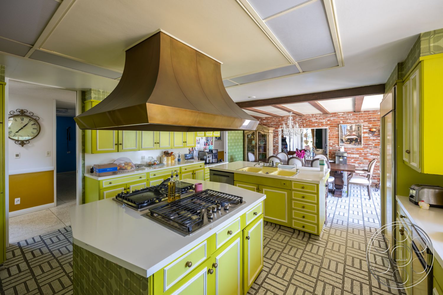 Euphoria - stainless steel appliances, brick accent wall, decorative chandelier, patterned tile flooring, green cabinetry, modern kitchen layout, open-concept kitchen, wood beam ceiling, built-in kitchen cabinets, white quartz countertops, exterior balcony view, copper range hood, farmhouse dining area