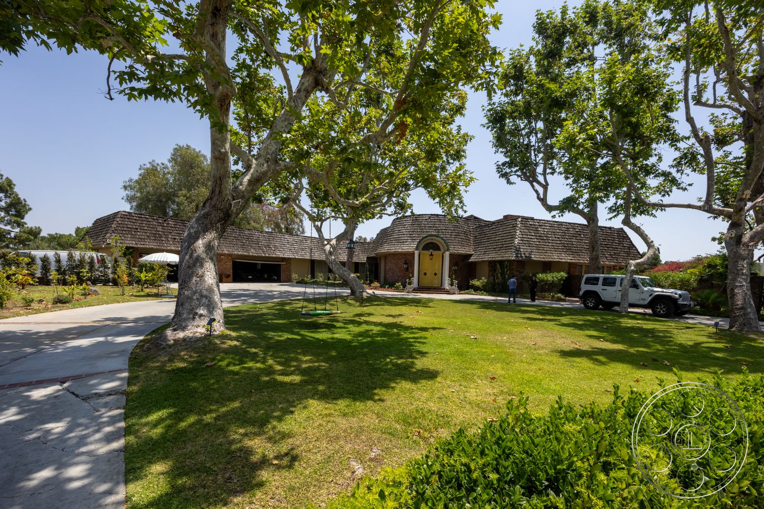 Euphoria - exterior, landscaped garden, garage door, mature trees, concrete driveway, arched entryway, double front doors, shingle roof, two-story home, brick exterior walls, spacious lawn area