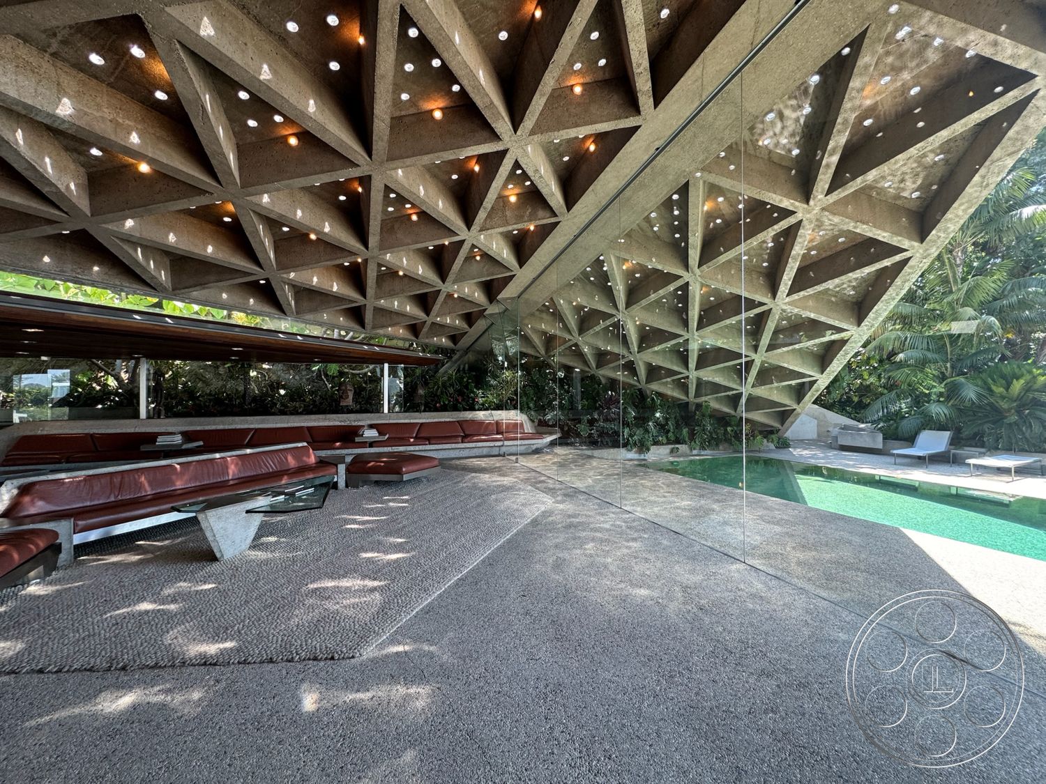 Goldstein House - exterior, glass walls, rectangular swimming pool, modern architectural style, stone patio flooring, LED ceiling lights, landscaped tropical garden, concrete ceiling with triangular grid, exposed concrete elements, red leather bench seating, textured aggregate concrete floor