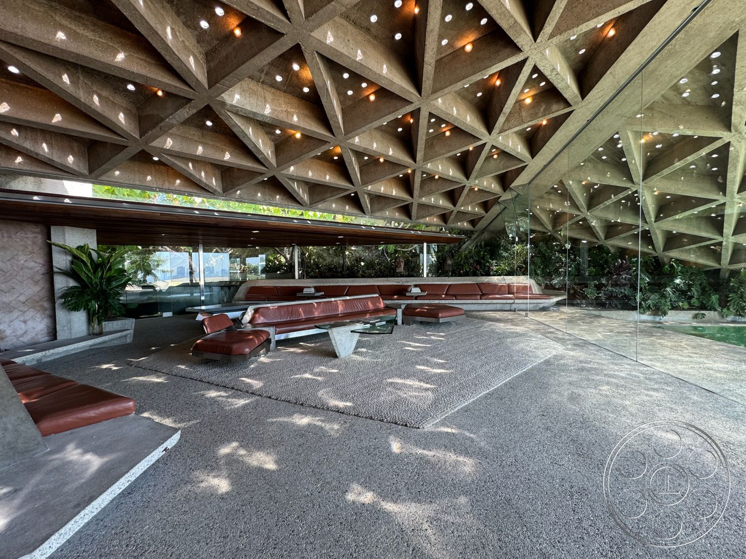 Goldstein House - exterior, polished concrete floor, modern architectural style, geometric ceiling design, leather sectional sofa, open floor plan layout, floor-to-ceiling glass walls, exposed concrete ceiling with triangular pattern, slate tile wall treatment, wooden overhead beams, designed outdoor garden space, integrated lighting features in ceiling